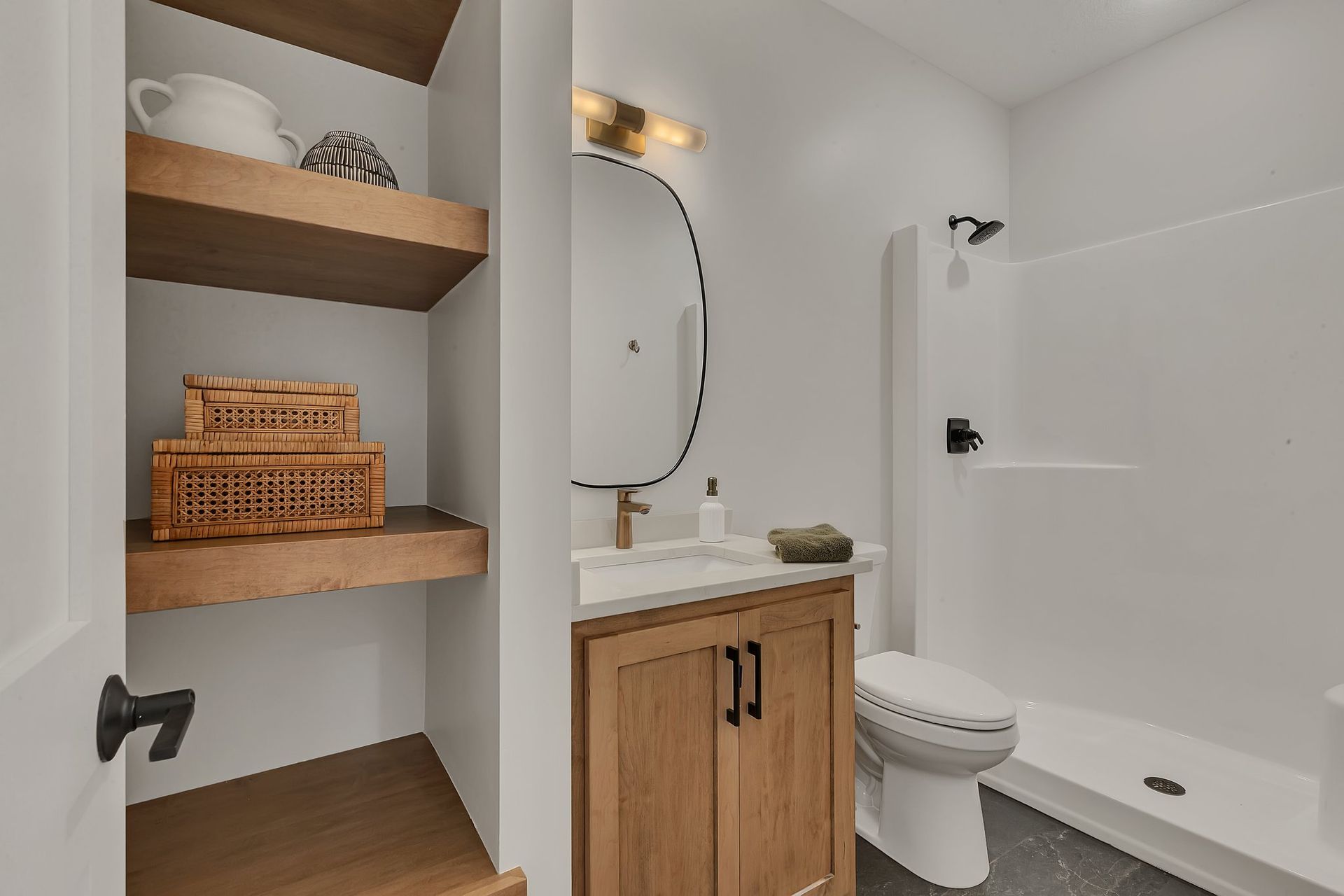 A bathroom with a sink , toilet , shower and shelves.
