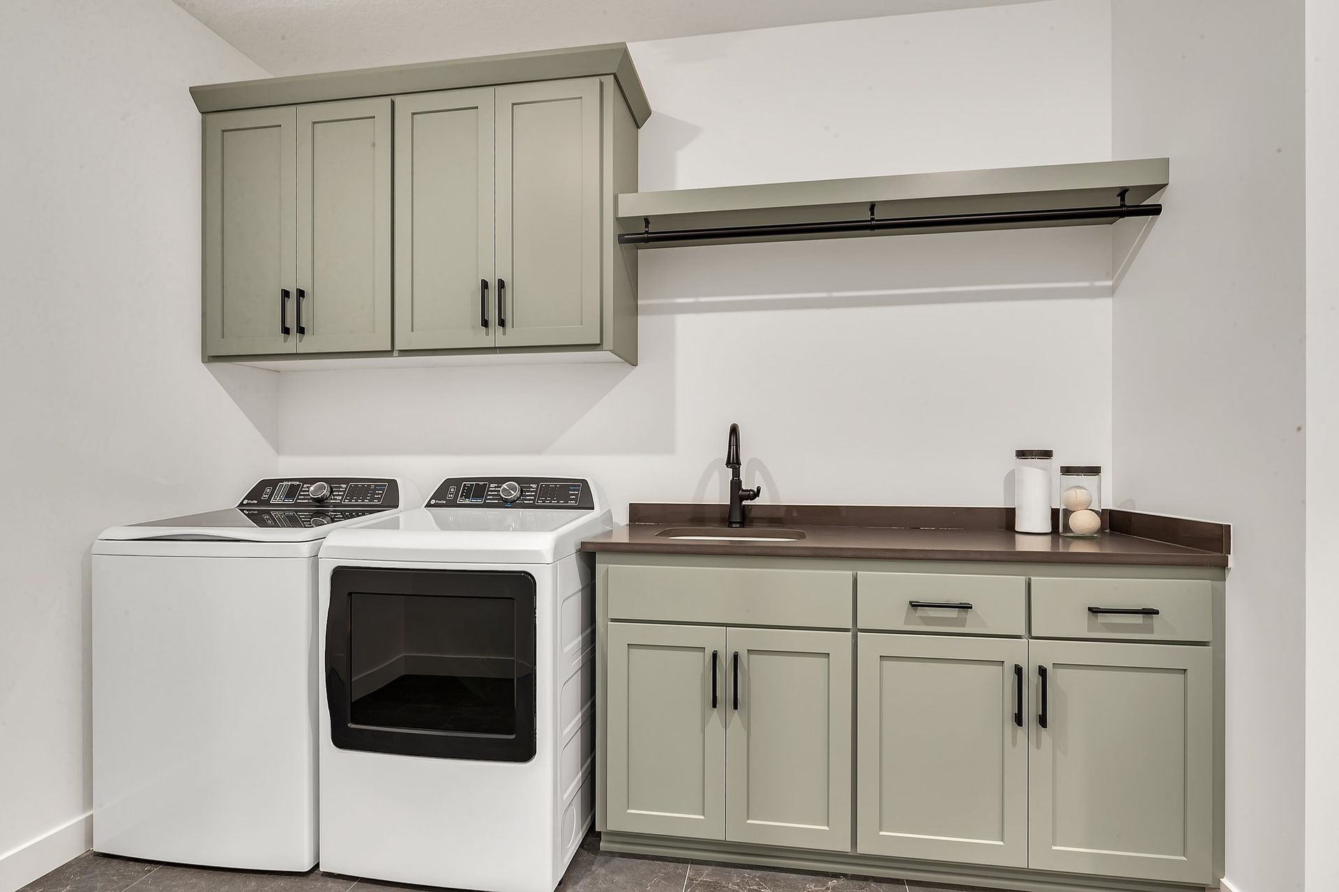 A laundry room with a washer and dryer , sink , and cabinets.