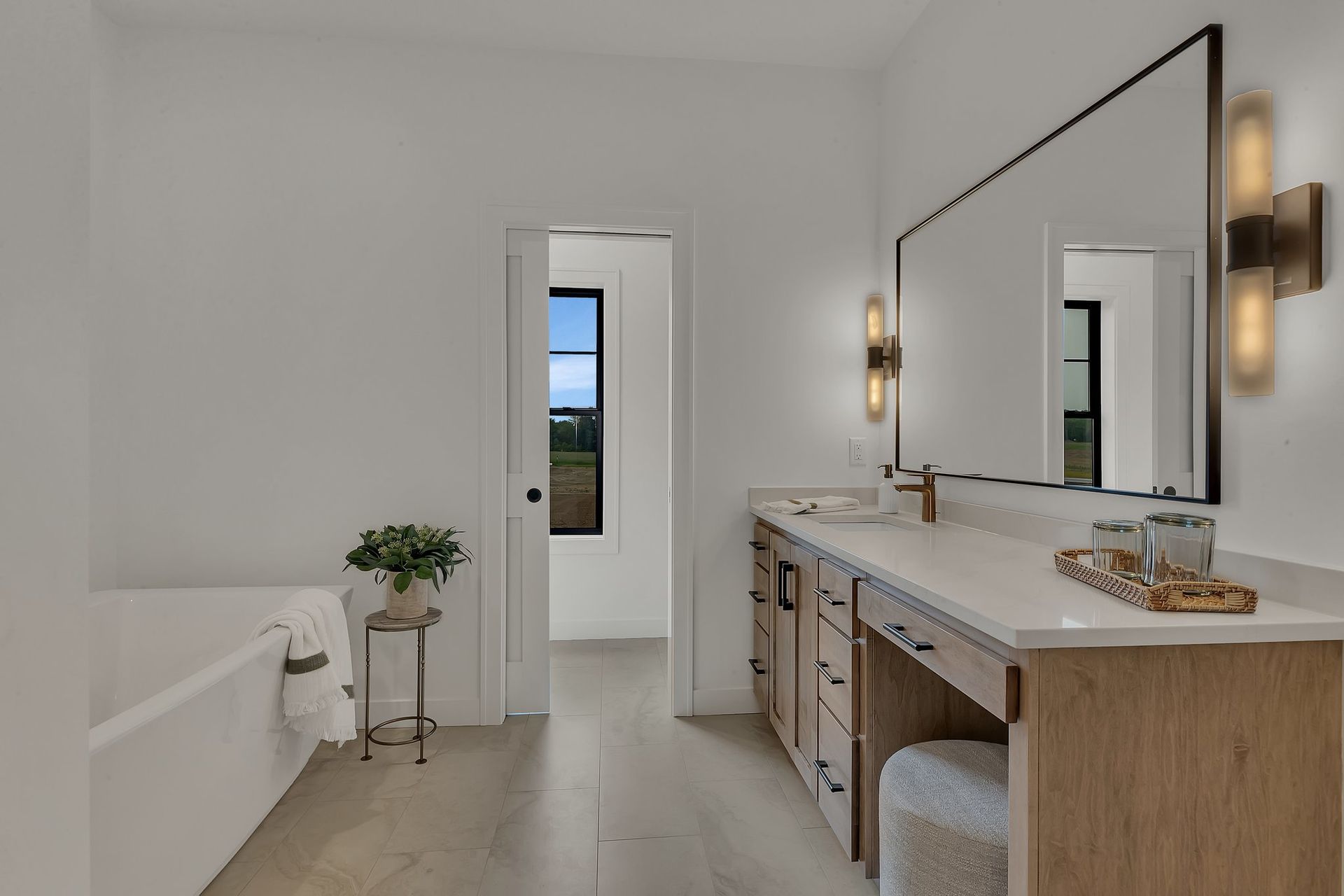 A bathroom with two sinks , a tub and a mirror.