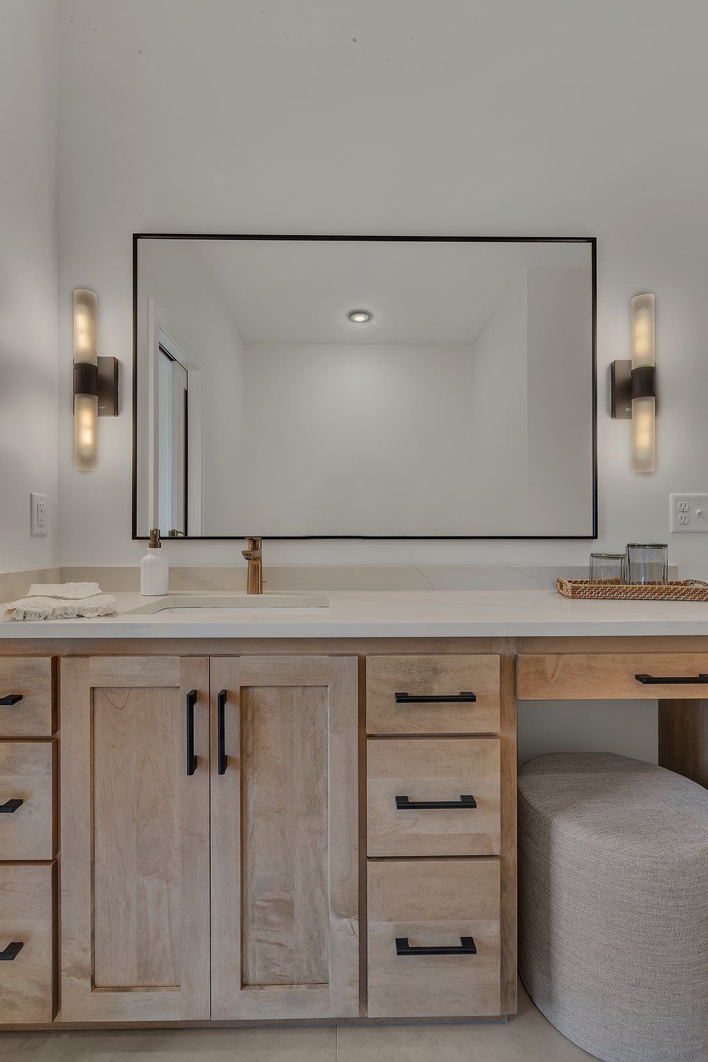 A bathroom with two sinks , a large mirror , and wooden cabinets.