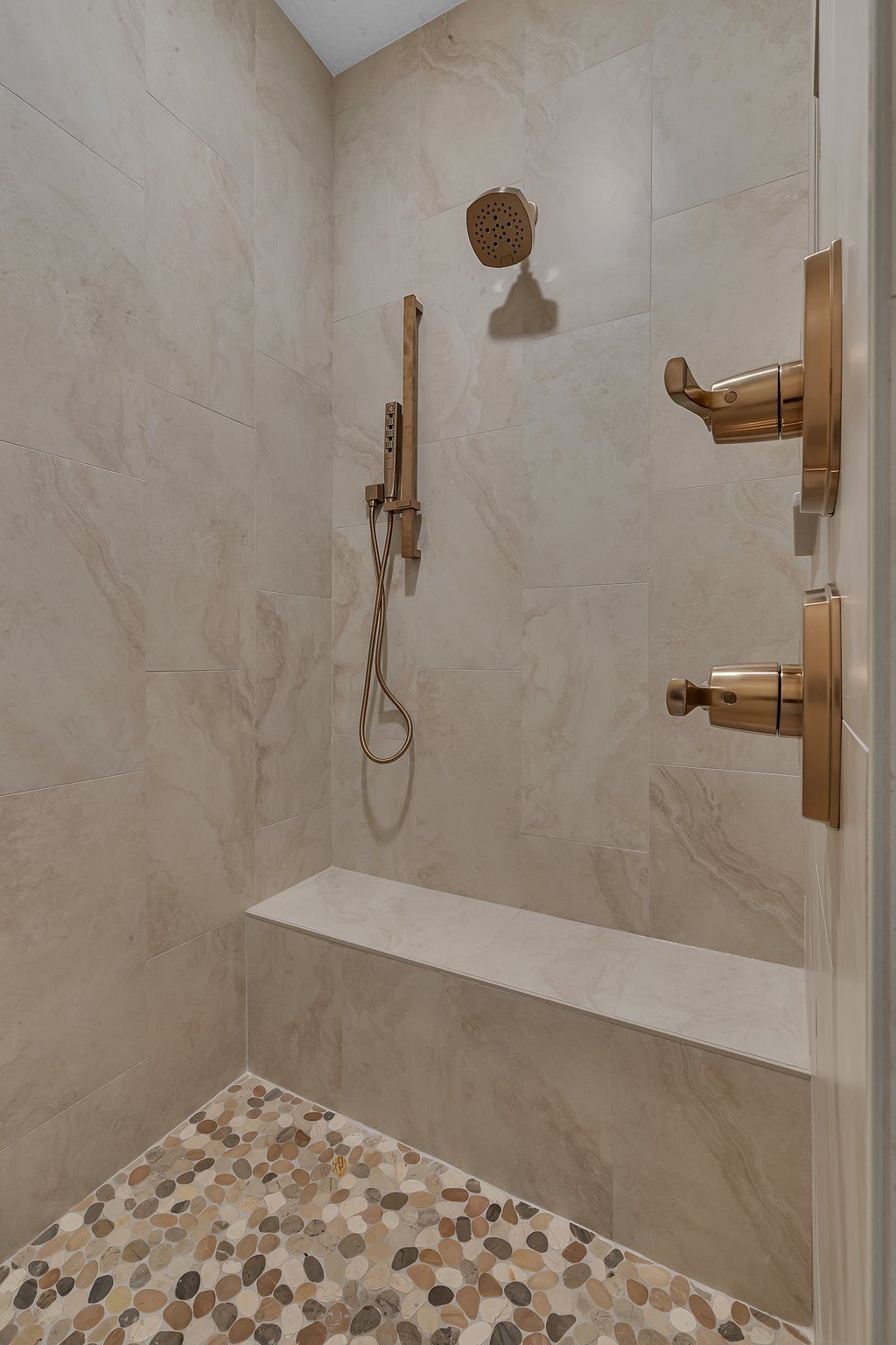 A bathroom with a walk in shower and a bench.