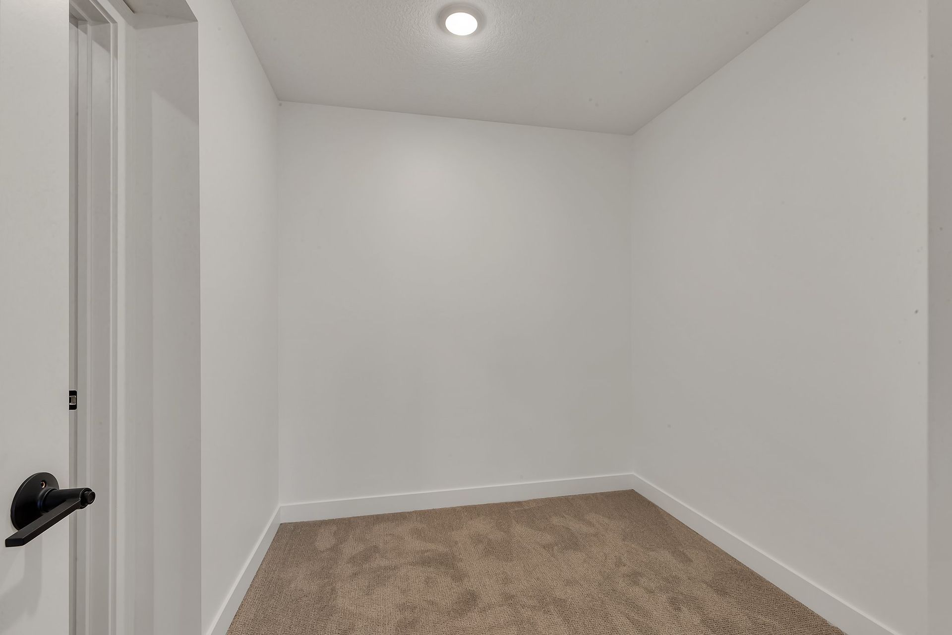 An empty room with a carpeted floor and white walls.
