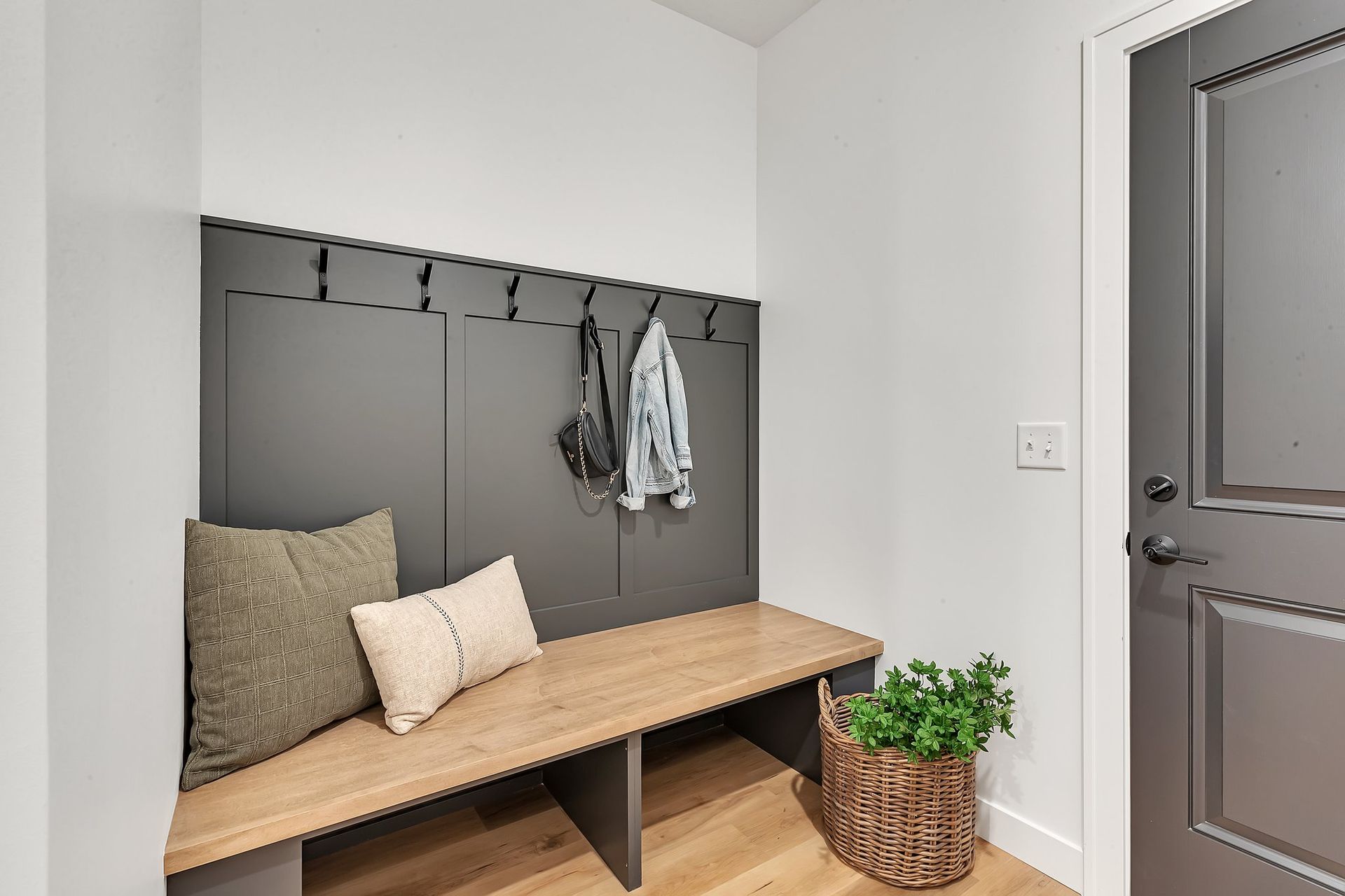 A hallway with a wooden bench and hooks on the wall.