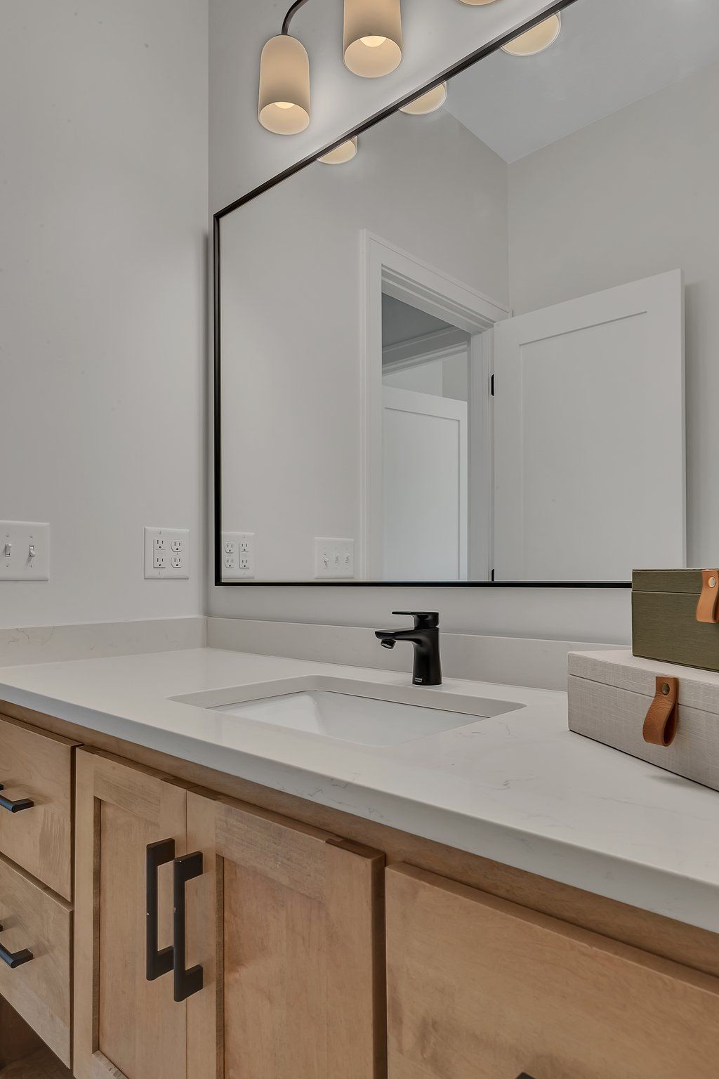 A bathroom with a sink , mirror and cabinets.