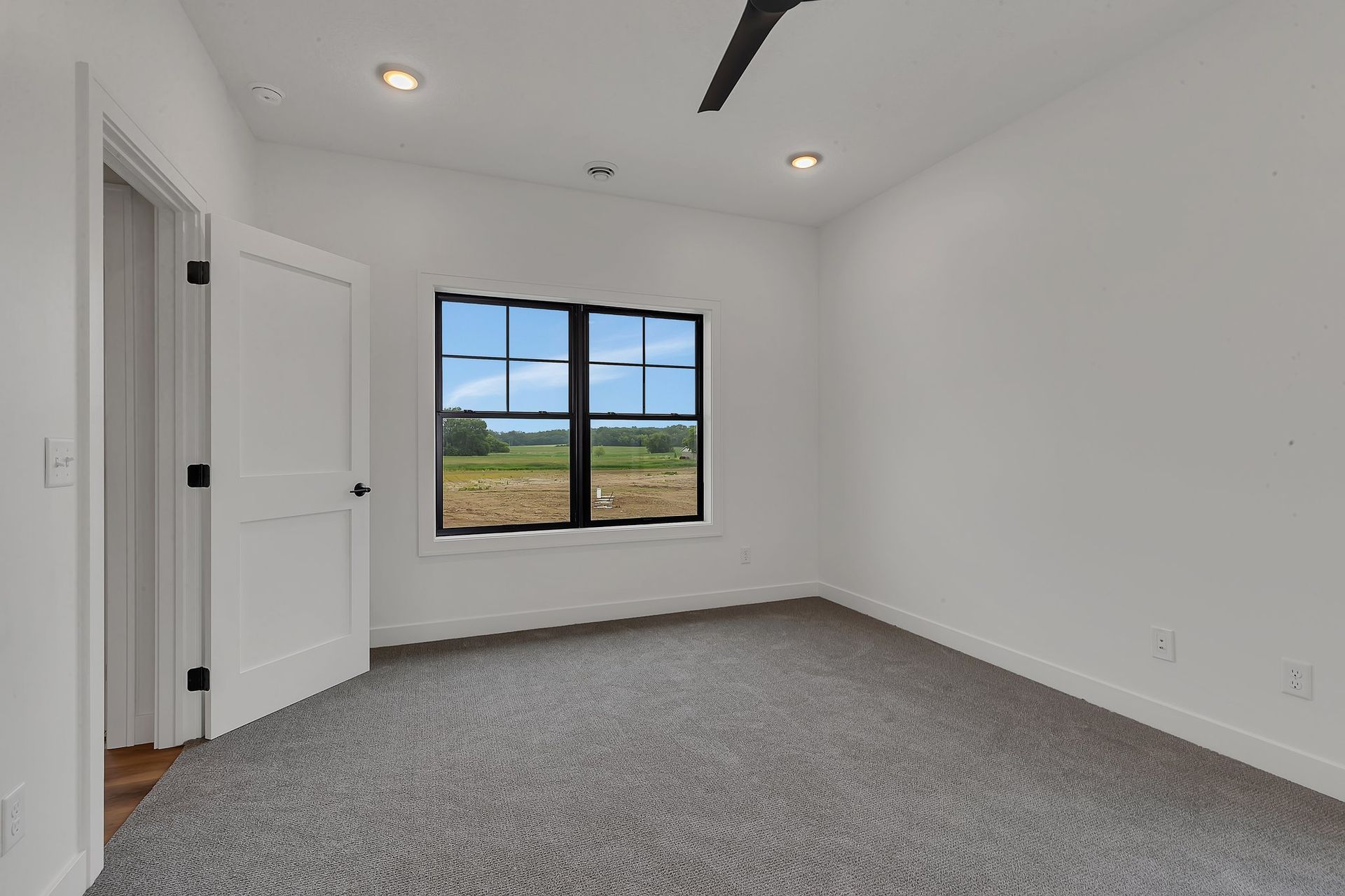 An empty bedroom with a window and a ceiling fan.