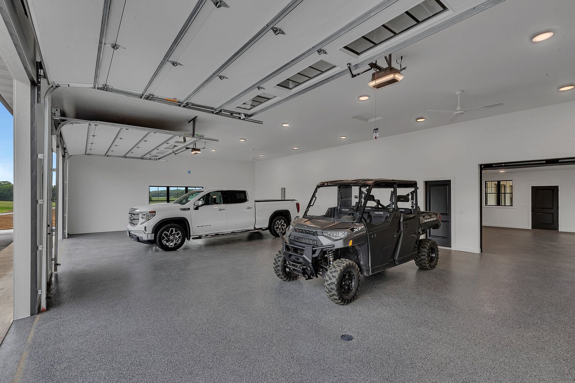 A garage with two cars and an atv in it.