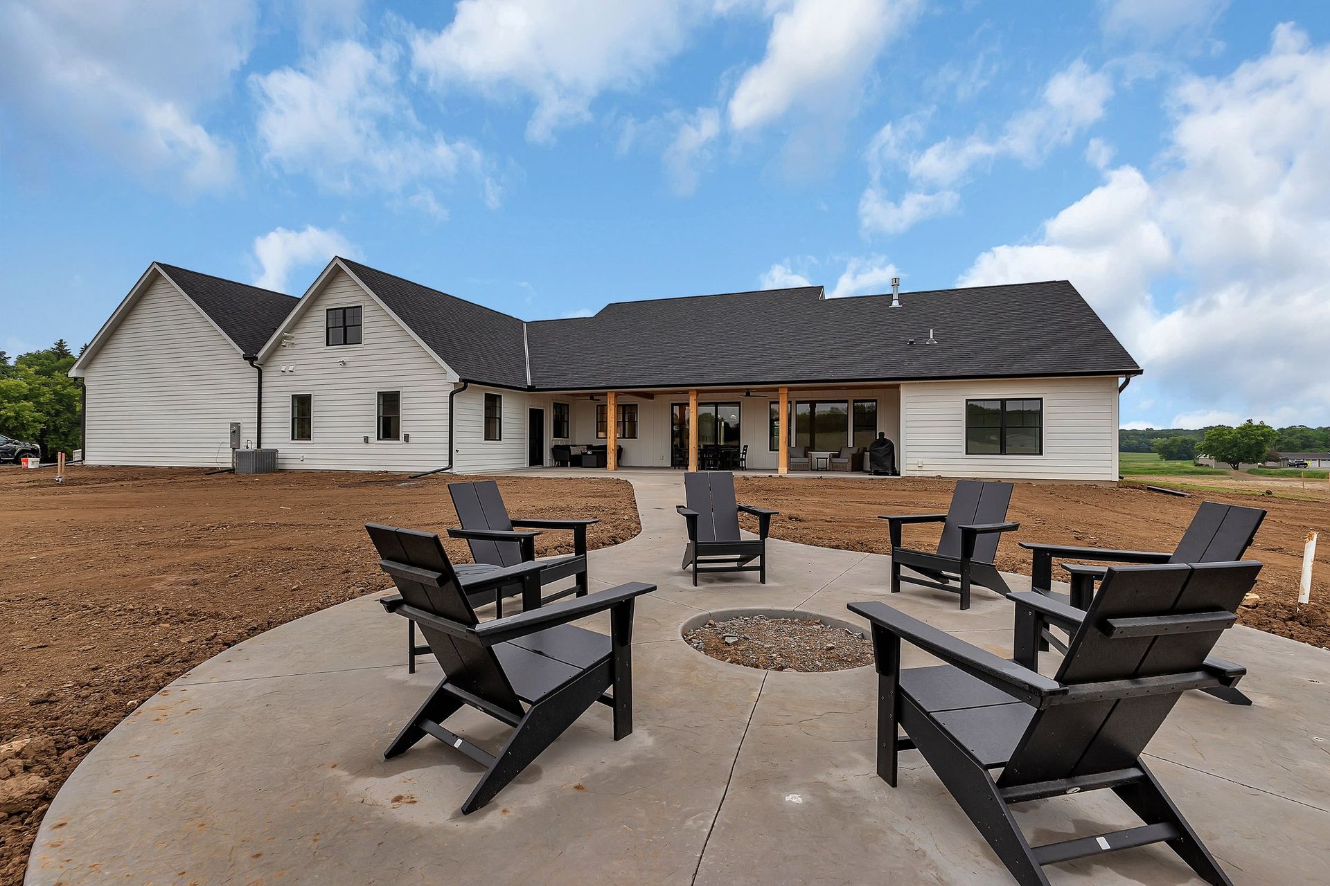 A patio with chairs and a fire pit in front of a house