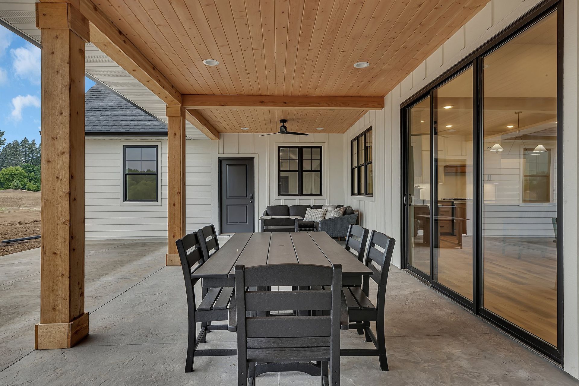 A patio with a table and chairs under a wooden roof