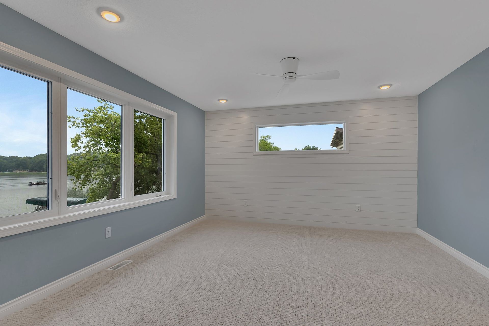 An empty room with a lot of windows and a view of a lake.