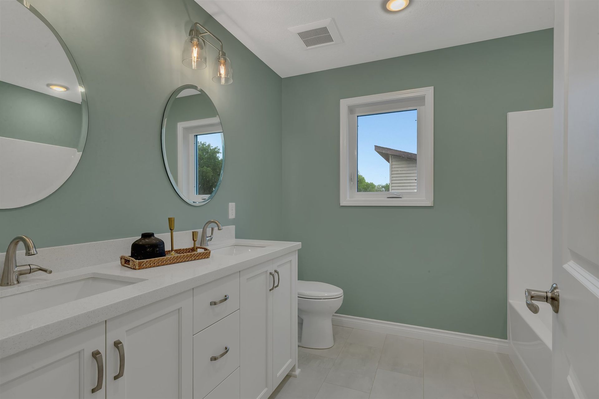 A bathroom with two sinks , a toilet , and a window.