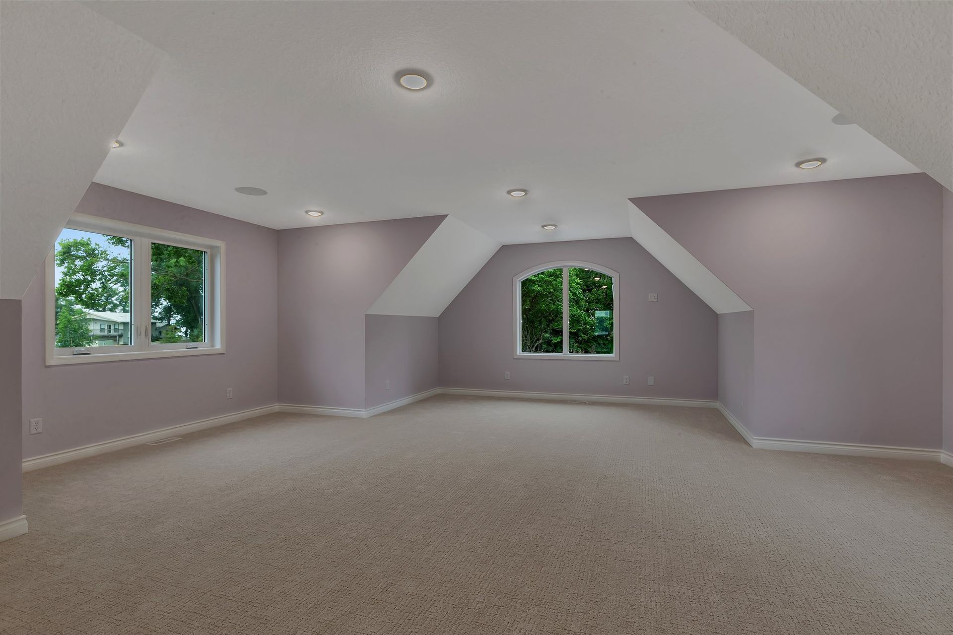 An empty room with a vaulted ceiling and two windows.