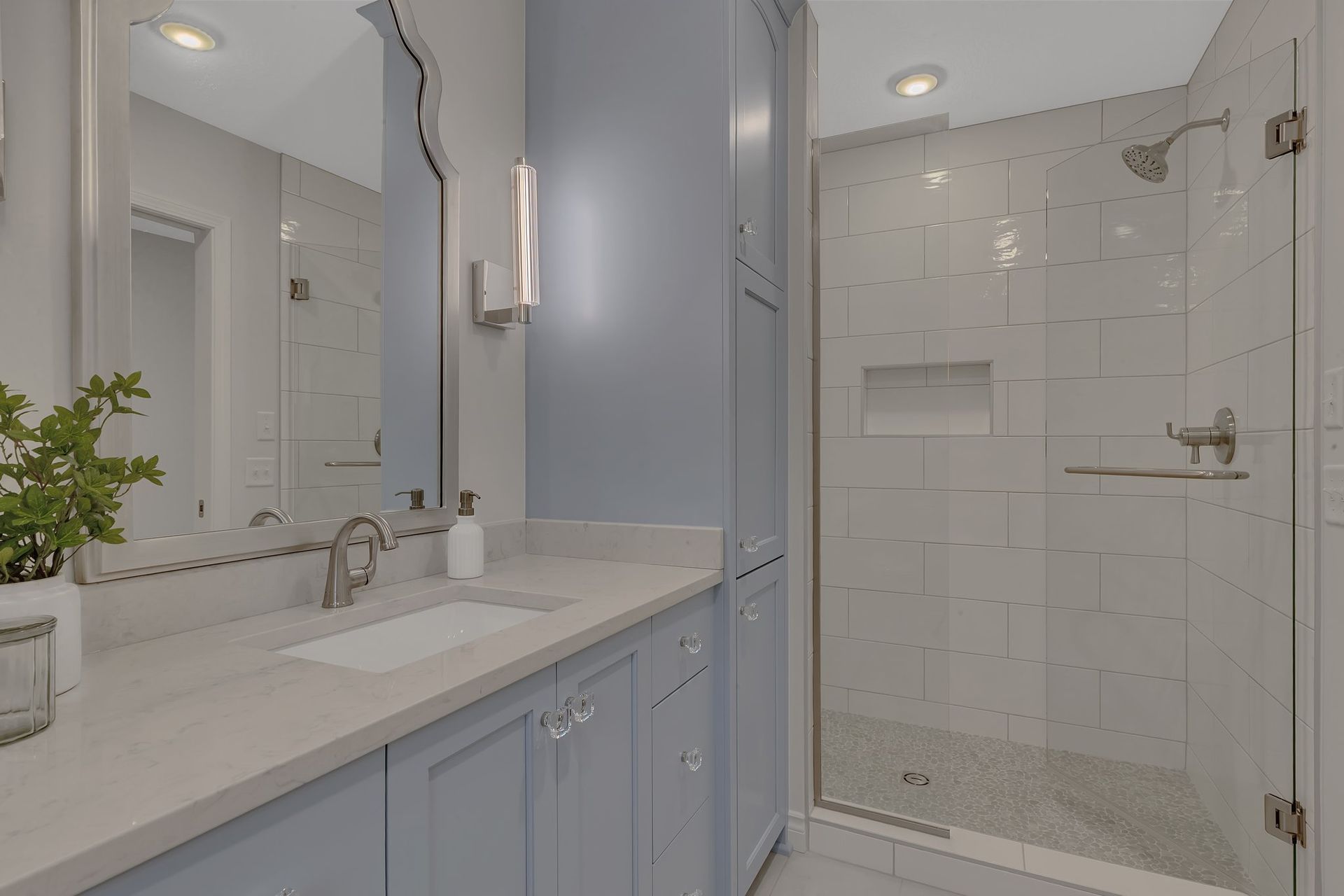 A bathroom with a sink , mirror , and walk in shower.