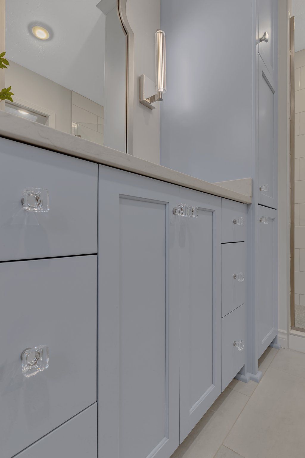 A bathroom with blue cabinets , drawers , a sink and a mirror.
