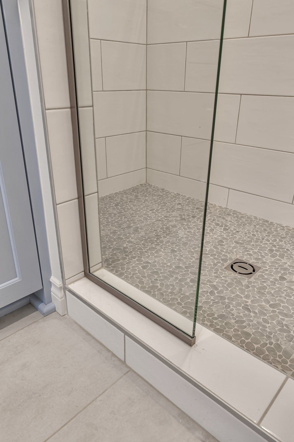 A bathroom with a walk in shower with a glass door.
