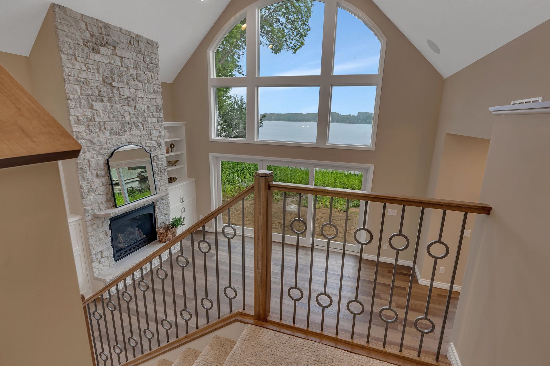 A staircase leading up to a living room with a fireplace and a view of a lake.