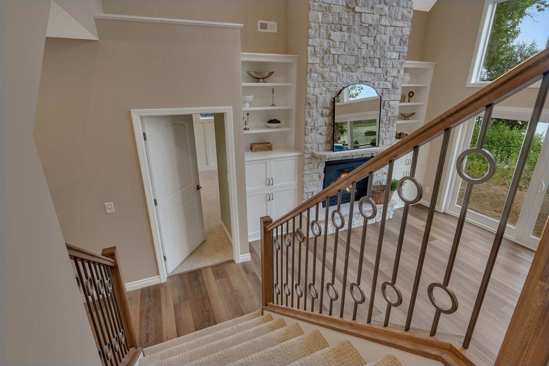 A staircase leading up to a living room with a fireplace and a mirror.