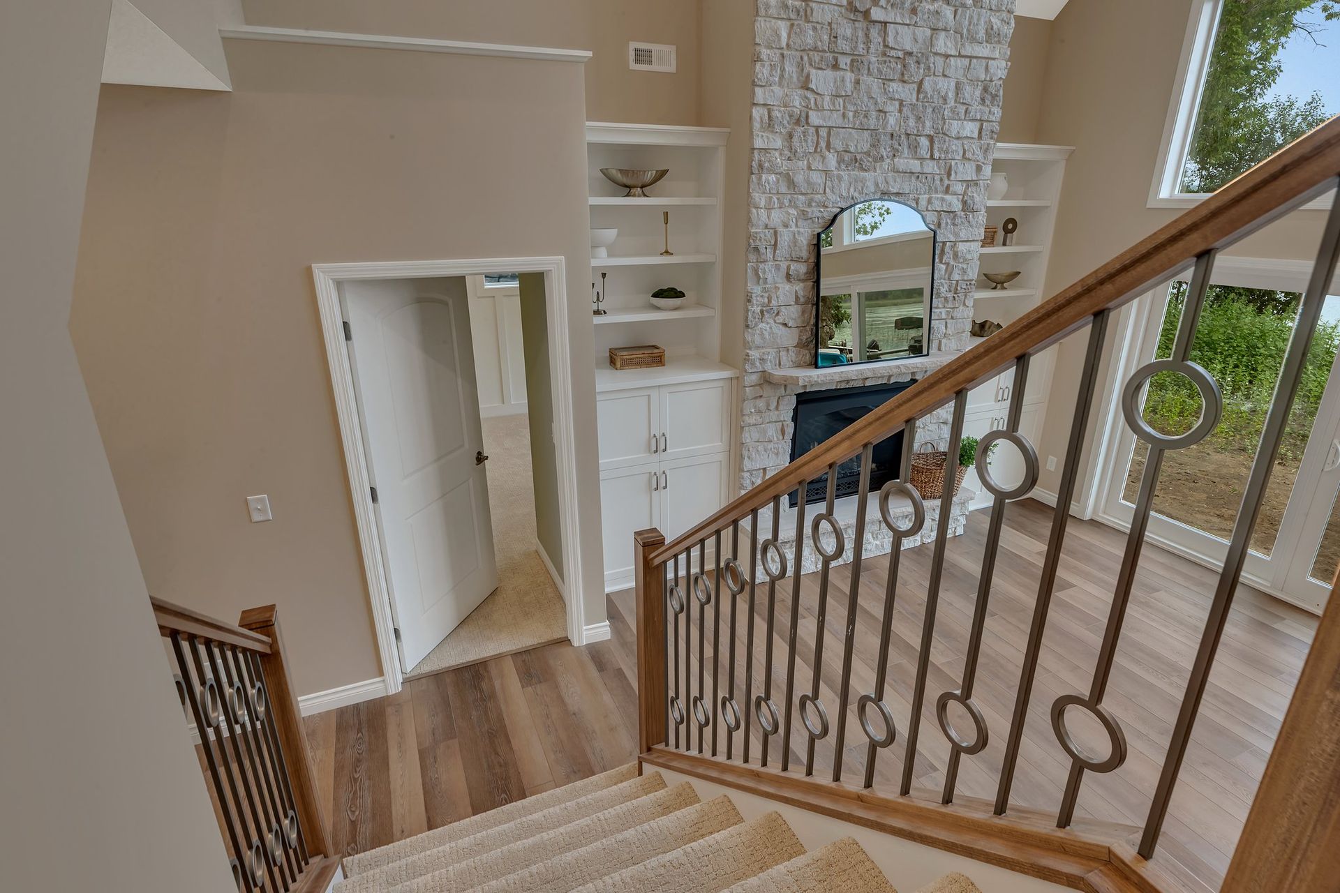 A staircase leading up to a living room with a fireplace and a mirror.