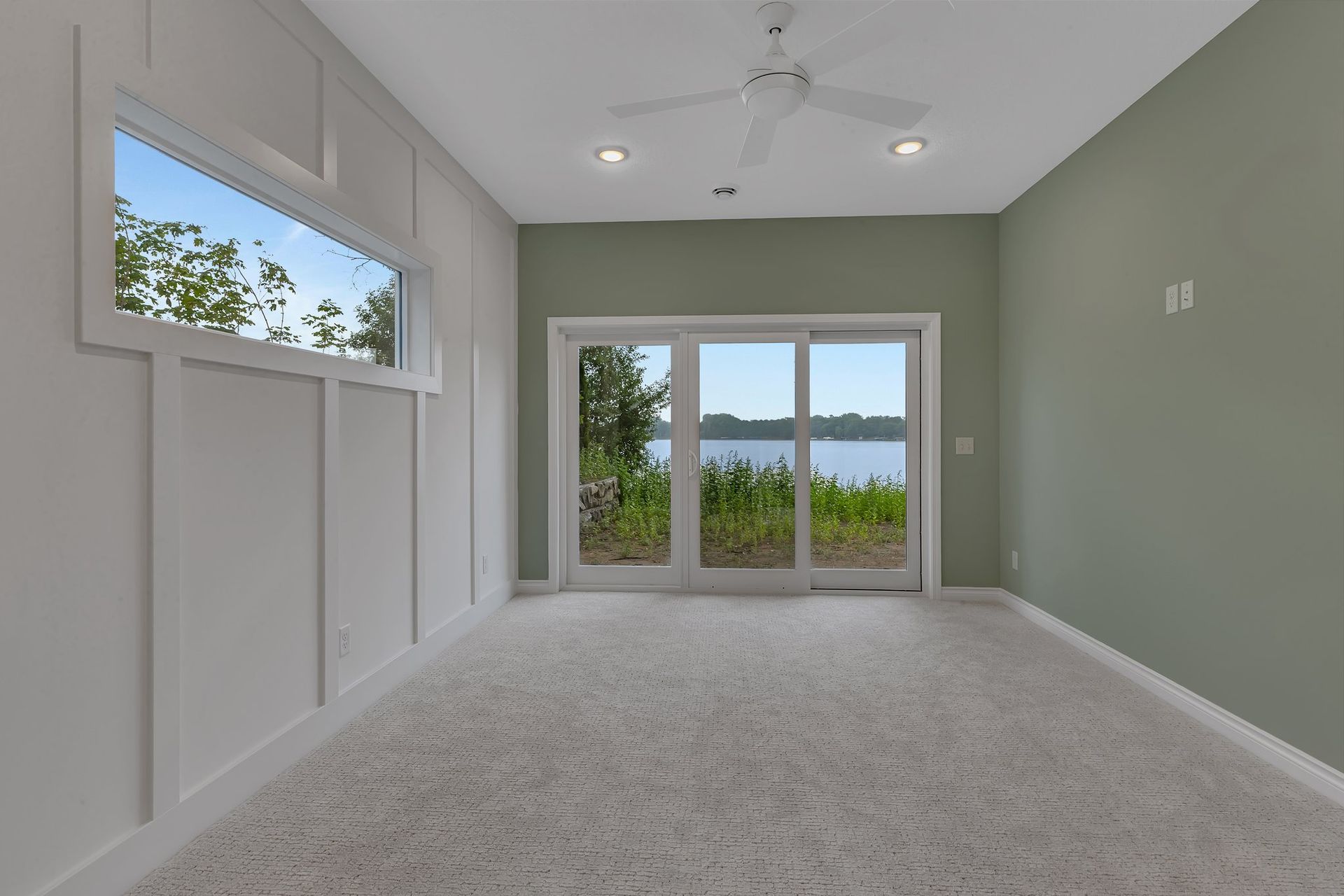 An empty room with sliding glass doors and a ceiling fan.