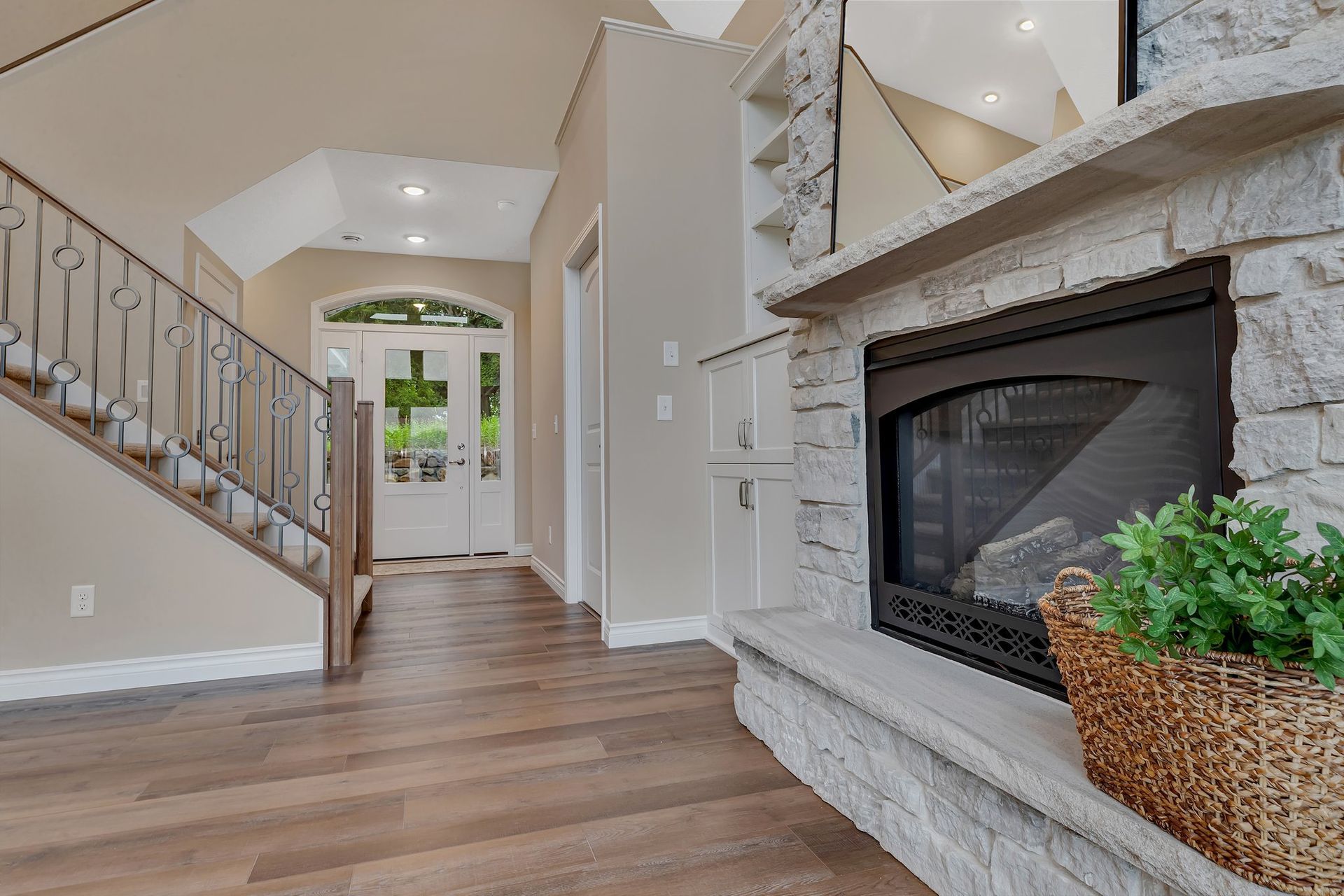 A living room with a fireplace and stairs in a house.