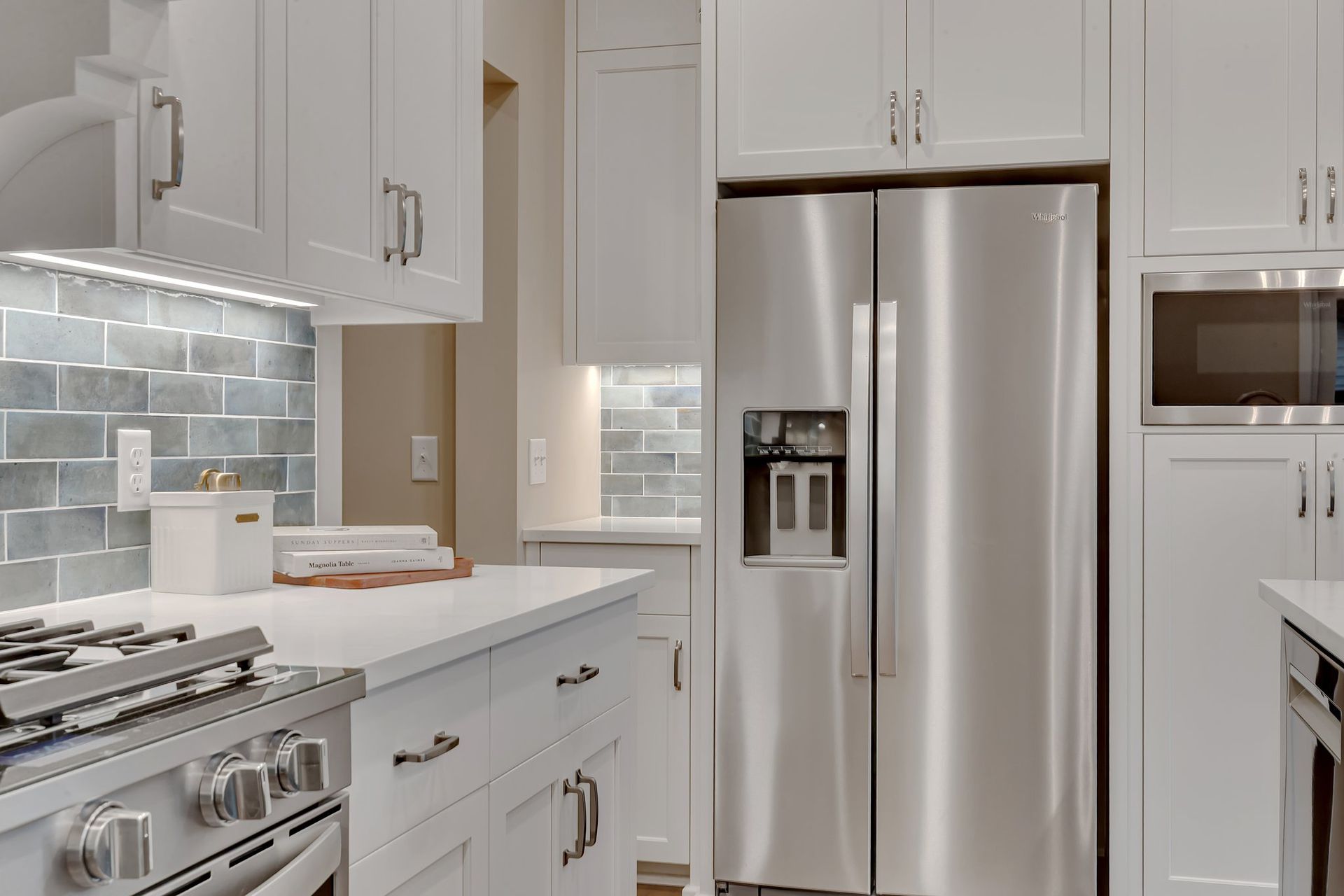 A kitchen with stainless steel appliances and white cabinets.