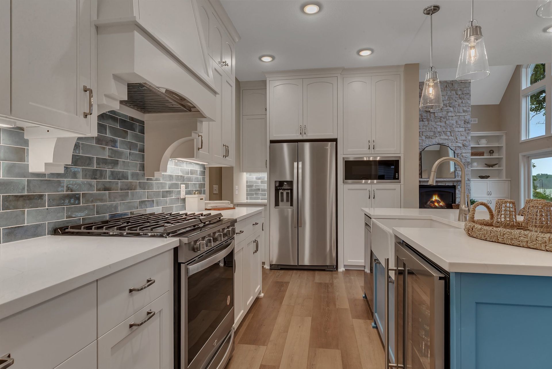 A kitchen with white cabinets , stainless steel appliances , and a blue island.