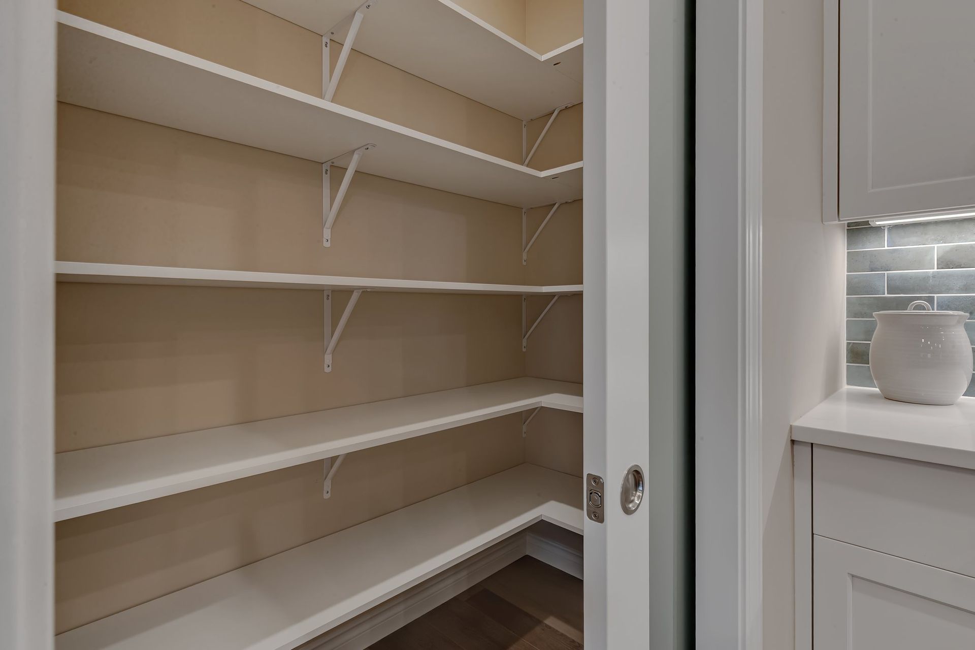 An empty pantry with white shelves and a sliding glass door.