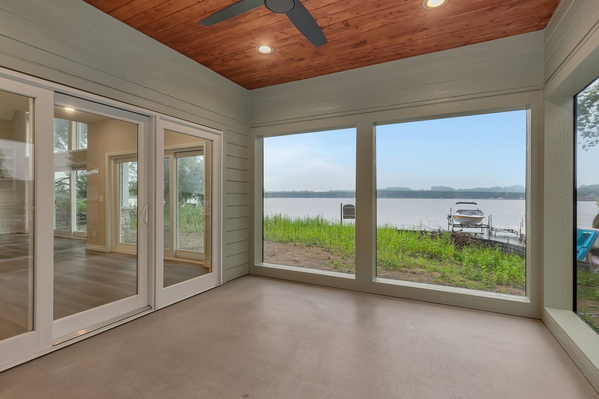 A room with a lot of windows and a view of a lake.