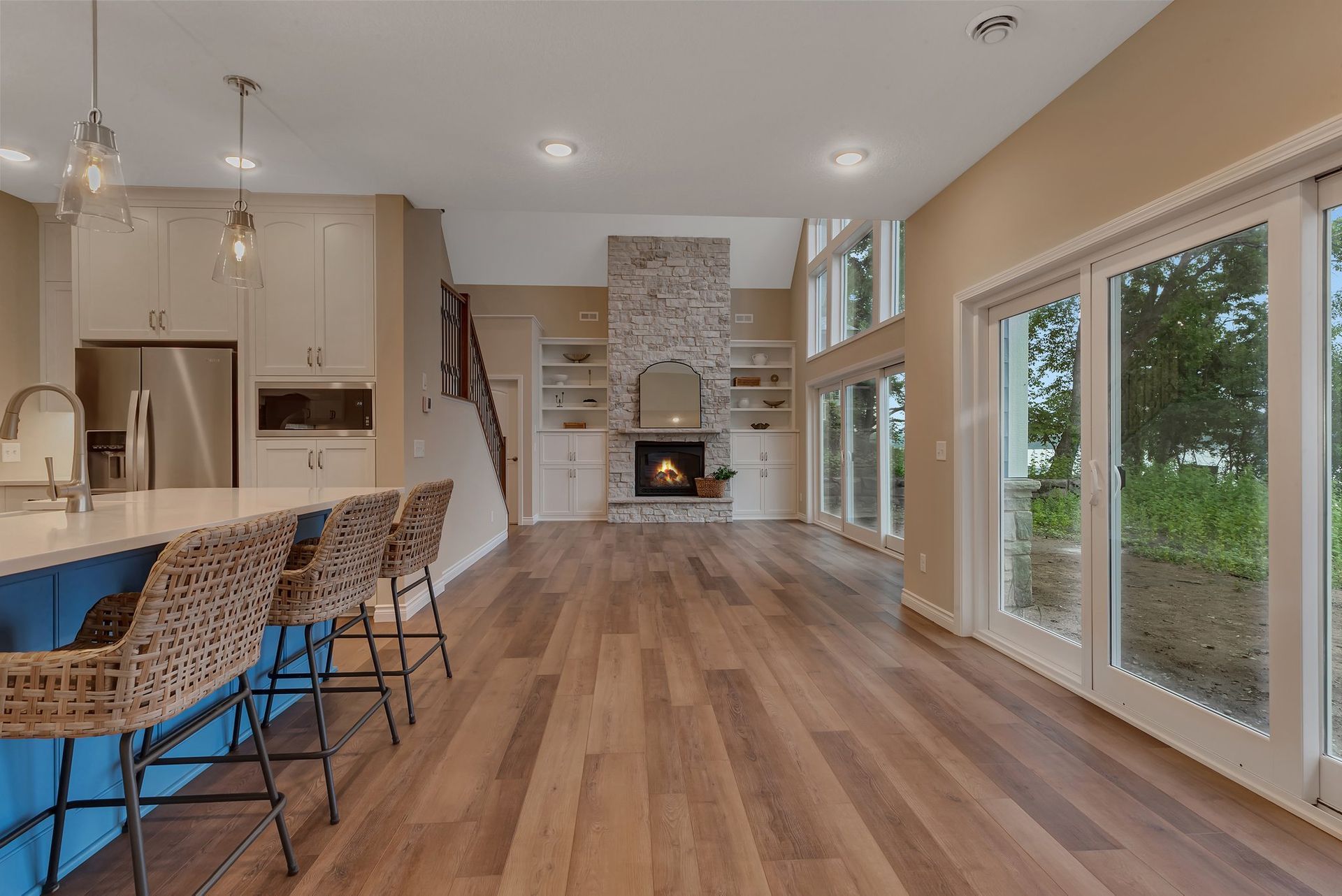 A kitchen with hardwood floors , a fireplace , sliding glass doors and a blue island.