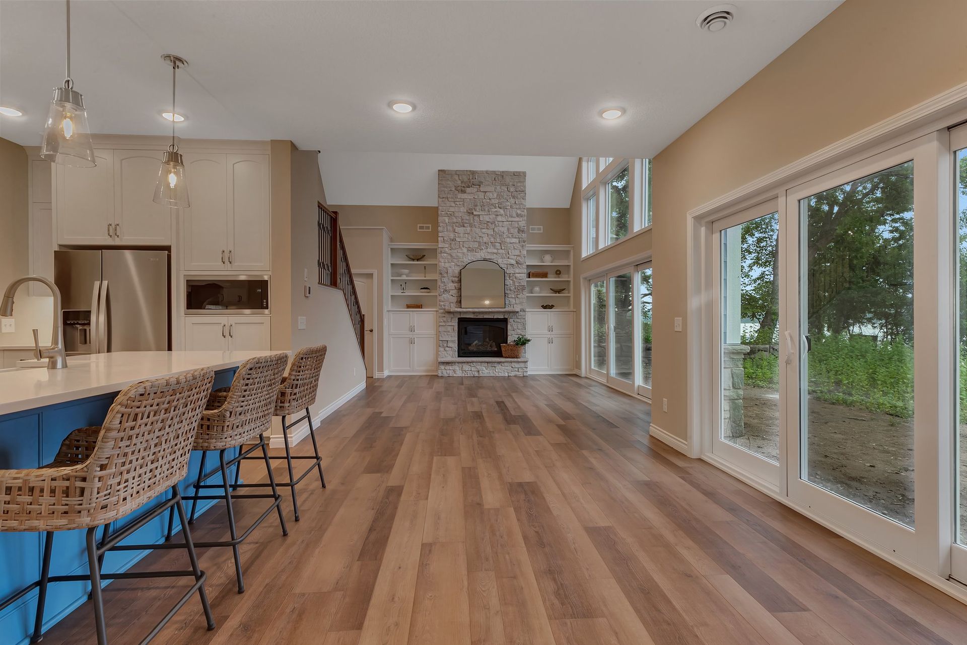 A kitchen and living room in a house with hardwood floors and sliding glass doors.