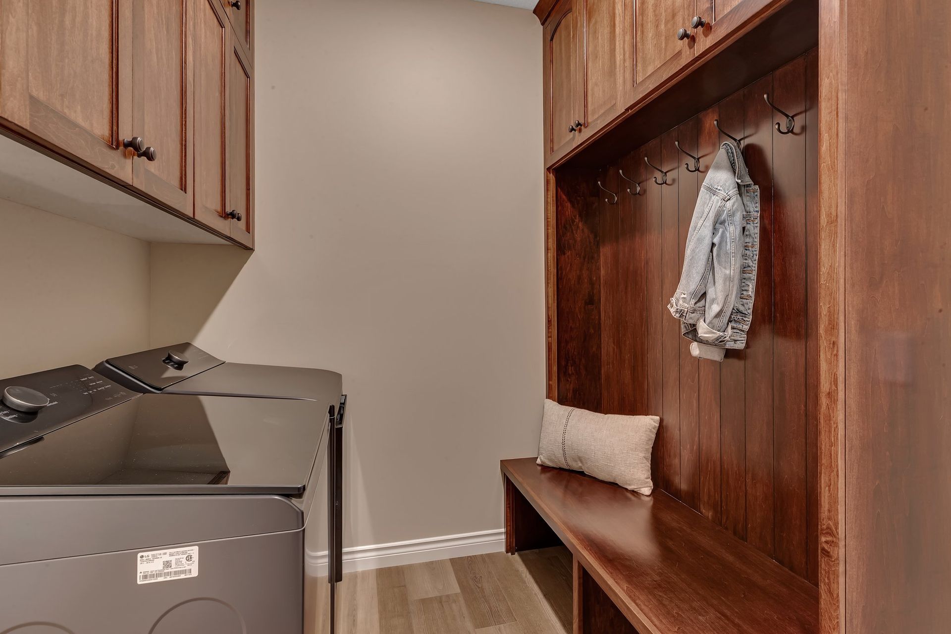 A laundry room with a washer and dryer and a bench.