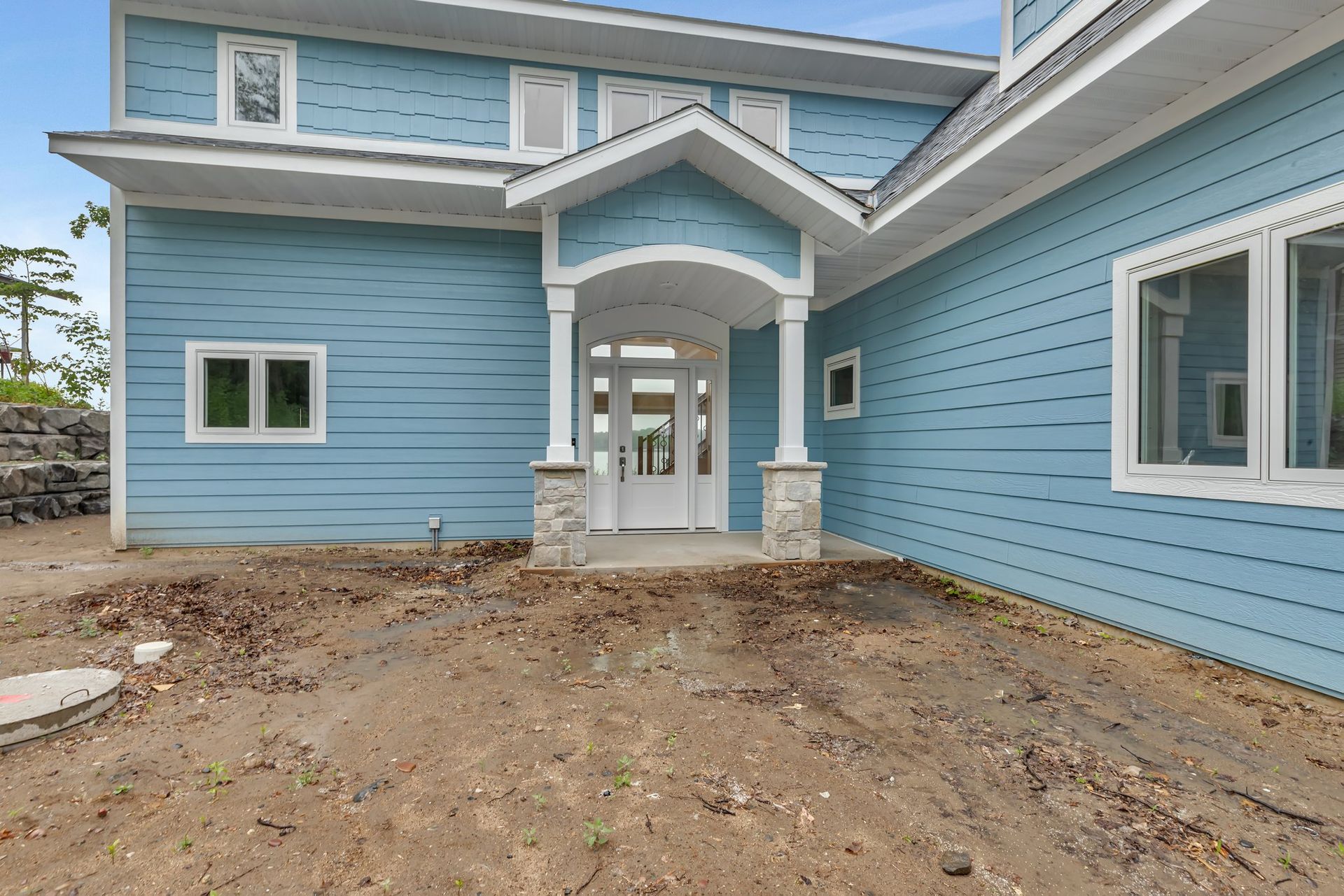 A blue house with a porch and a lot of windows
