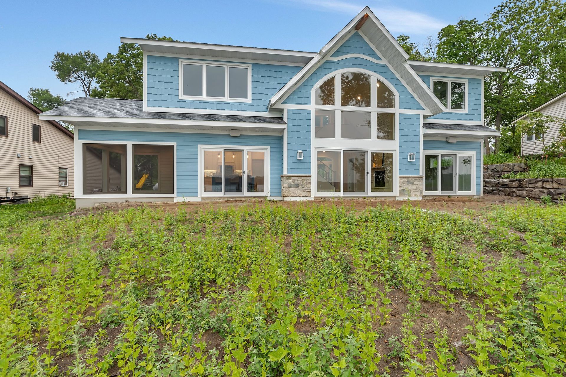 A large blue house with a lot of windows is sitting on top of a grassy hill.