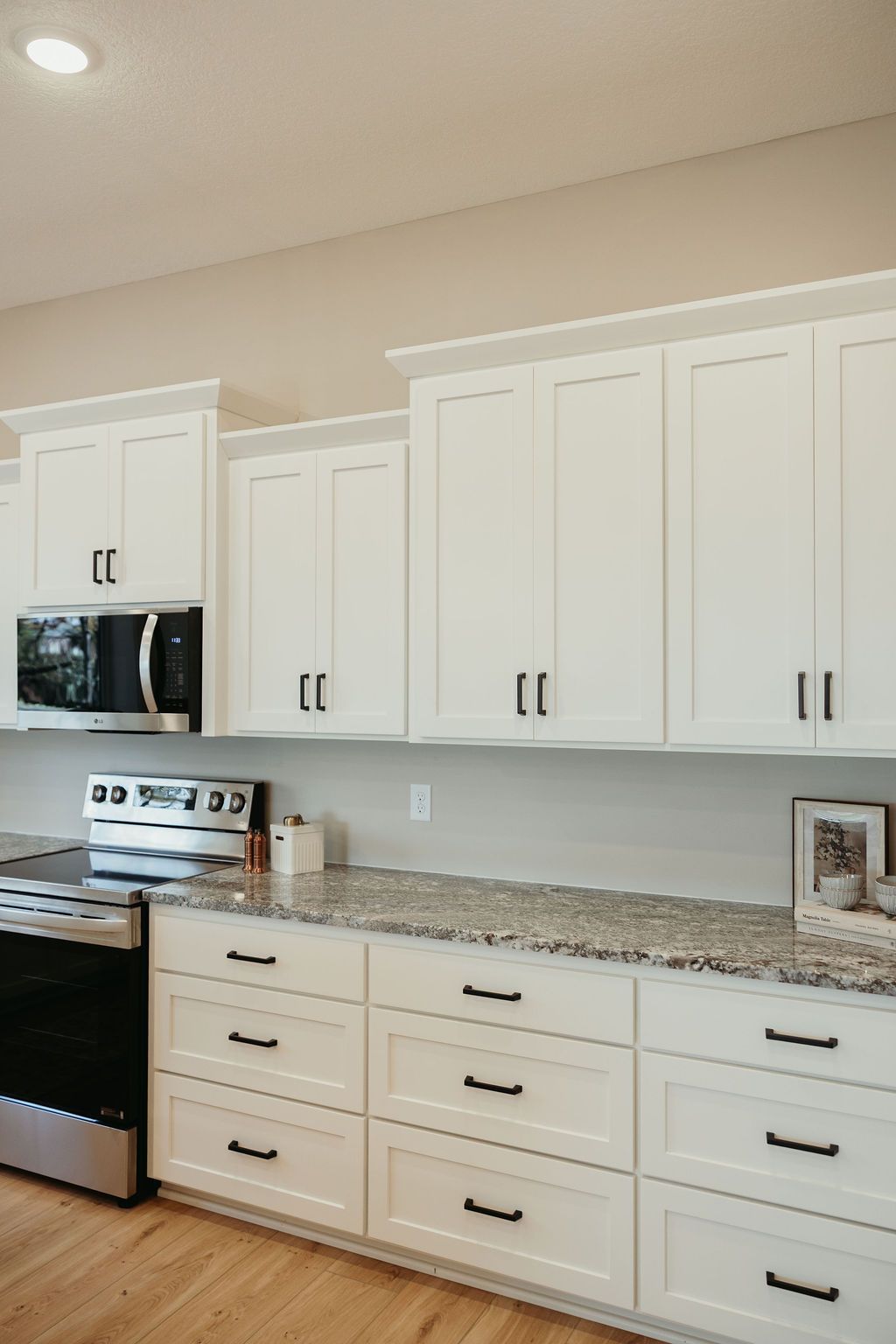 White kitchen cabinets with black hardware and a granite countertop.