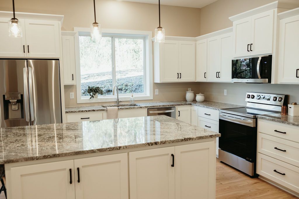 White kitchen with granite countertops and stainless steel appliances.