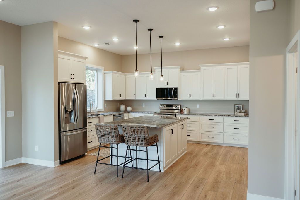 Modern kitchen with white cabinets, stainless steel appliances, and a gray island with seating.