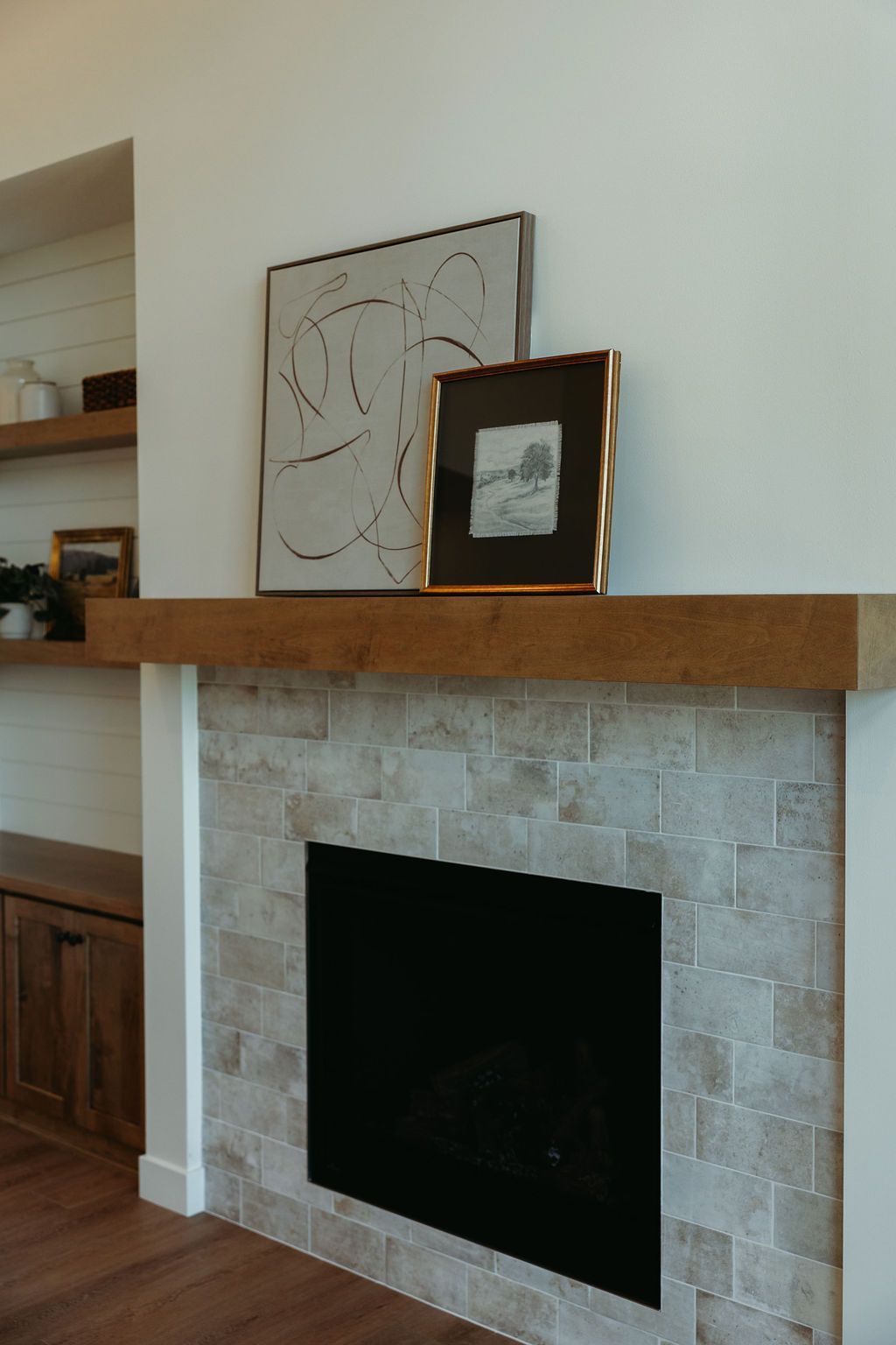 Fireplace with stone tile surround, wooden mantel, and artwork.
