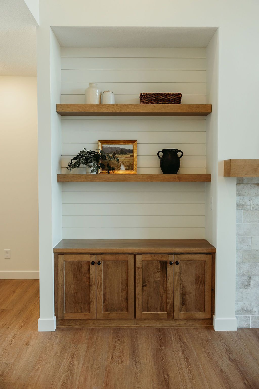 Built-in wooden shelving unit with cabinets, two shelves, and shiplap background.