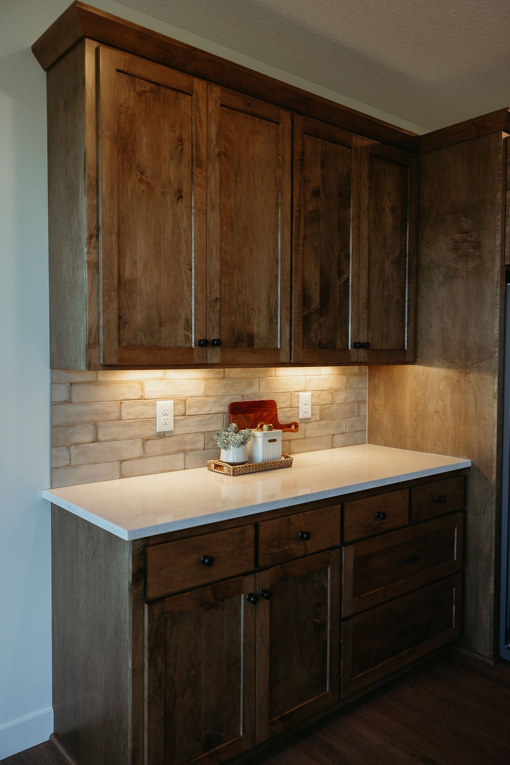 Wooden kitchen cabinets with a white countertop and brick backsplash.
