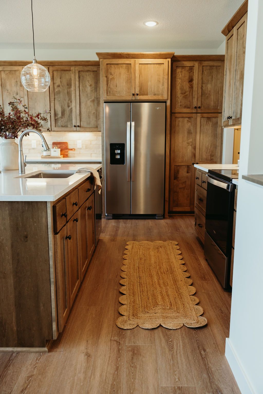 Kitchen with wood cabinets, stainless steel appliances, and a runner rug.