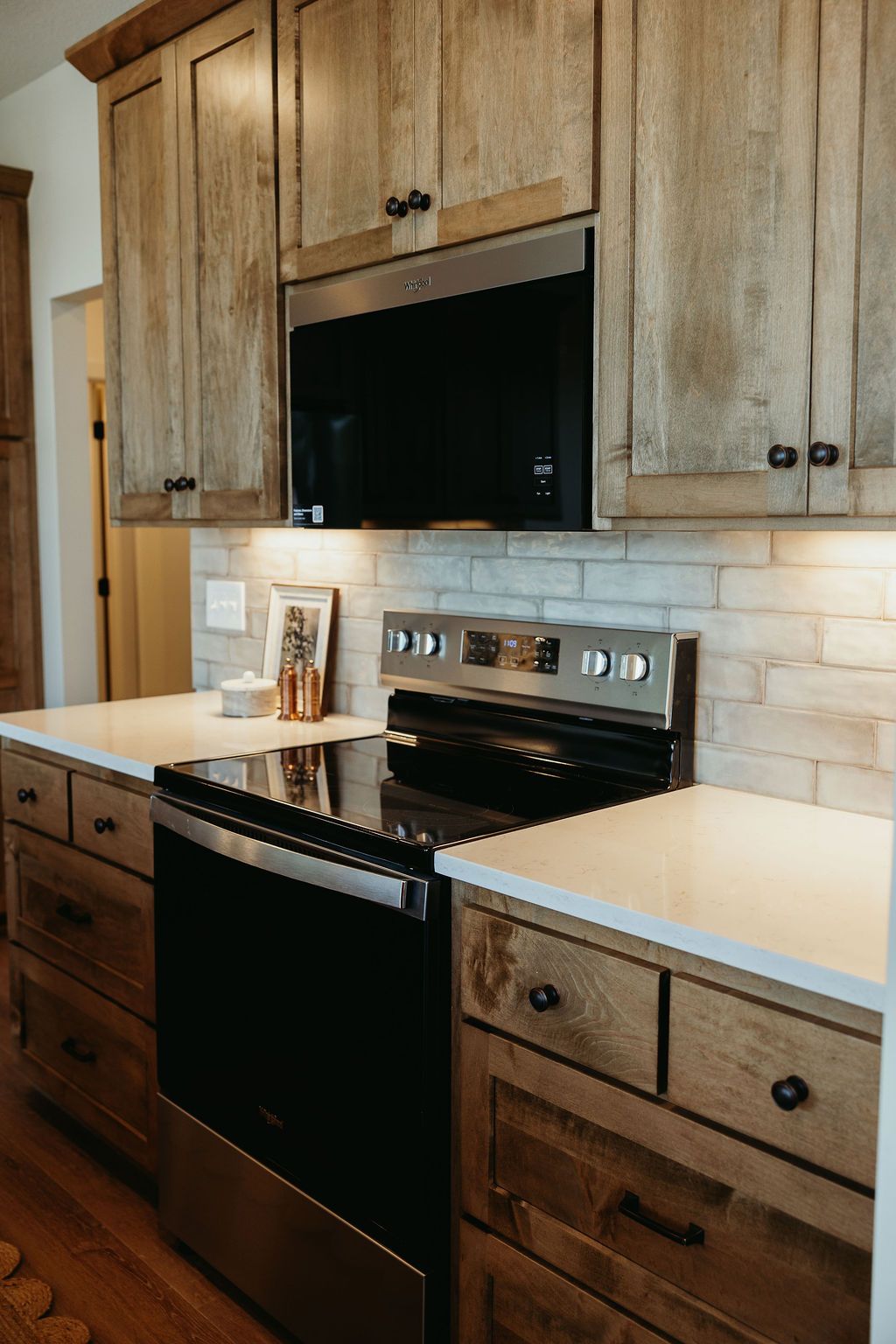 Kitchen with rustic wooden cabinets, stainless steel appliances, and white countertops.