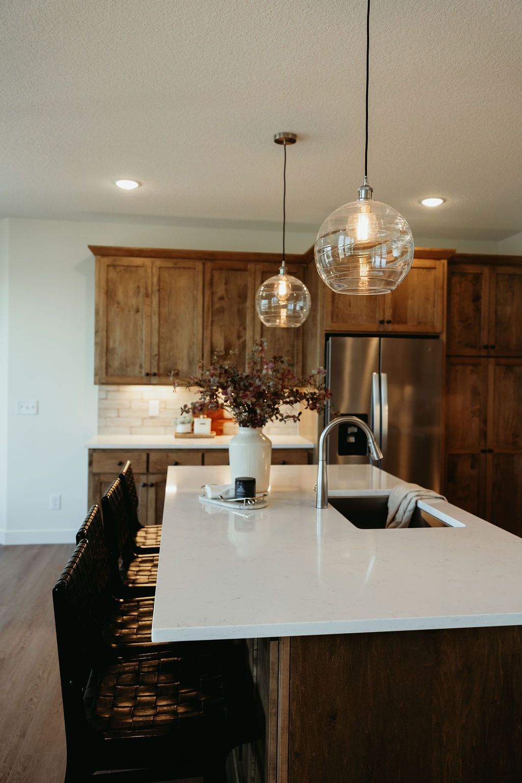 Kitchen with white countertop island, dark wood cabinets, and globe pendant lights.