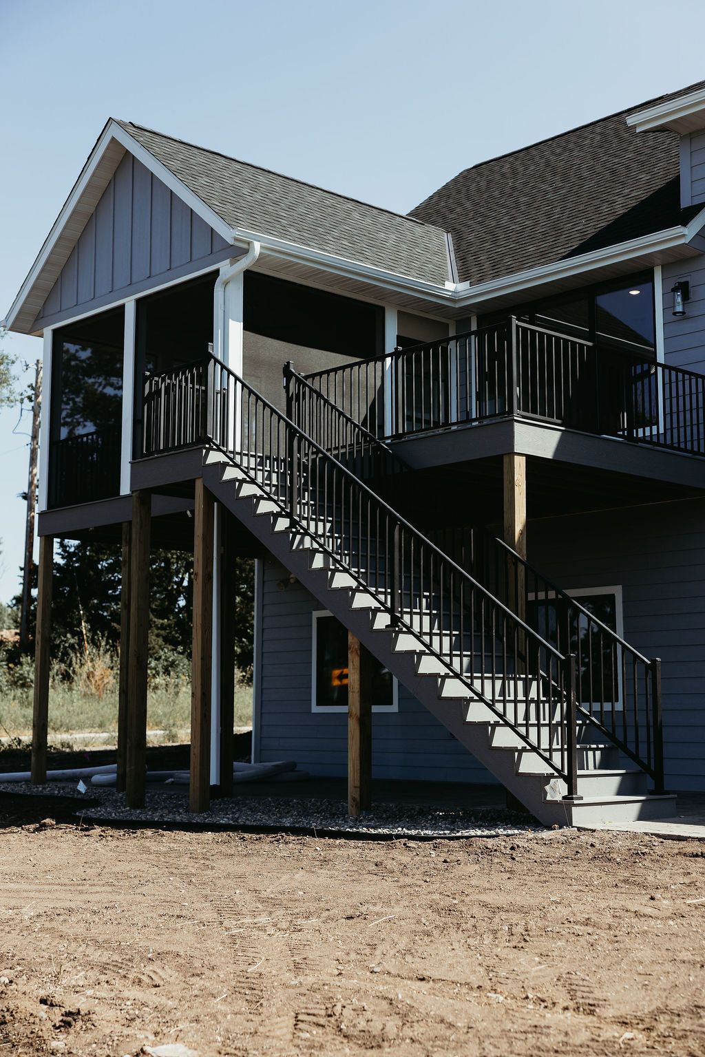 Gray house with dark stairs leading to screened porch and upper deck.