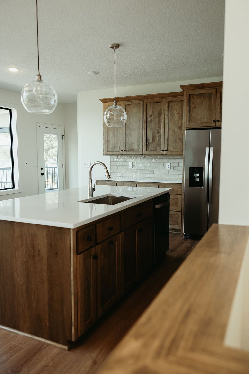 Kitchen with wood cabinets, white countertops, stainless steel appliances, and pendant lights.