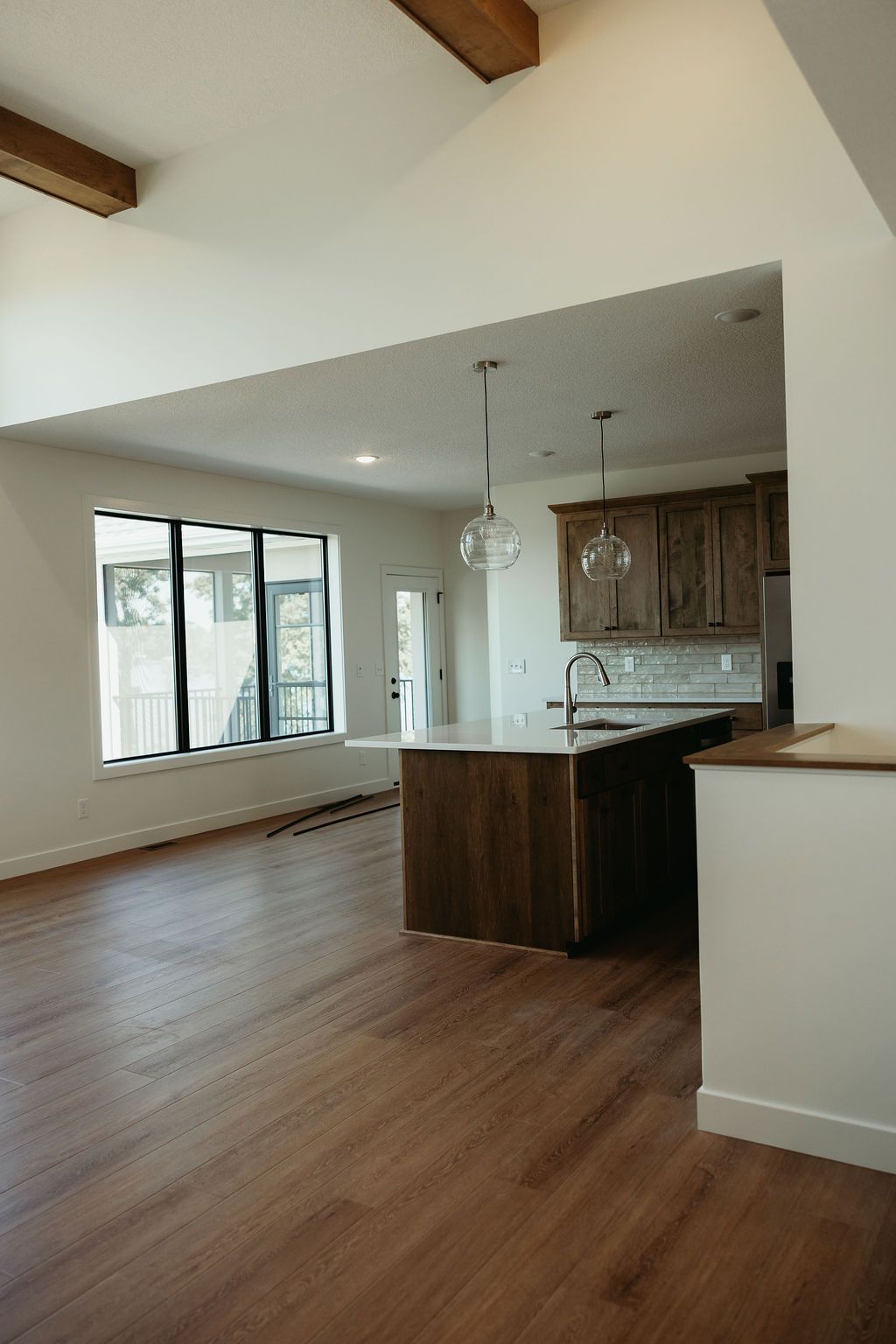 Interior view of a modern kitchen with a wooden island, cabinets, and light fixtures.