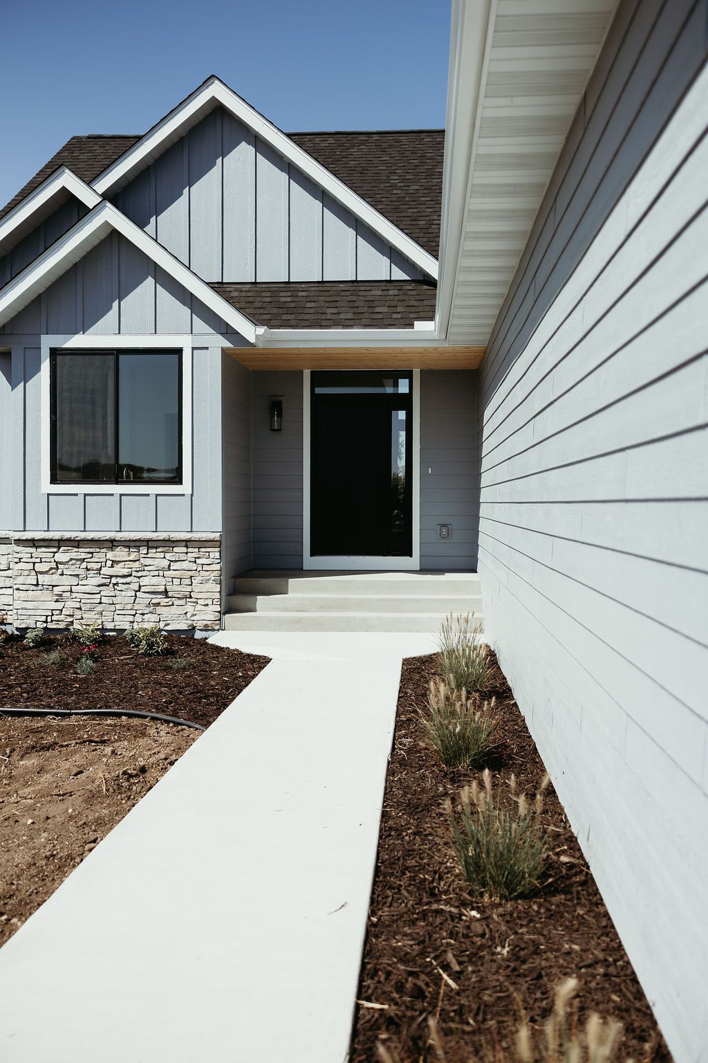 Exterior view of a modern house with a blue exterior and a concrete walkway.