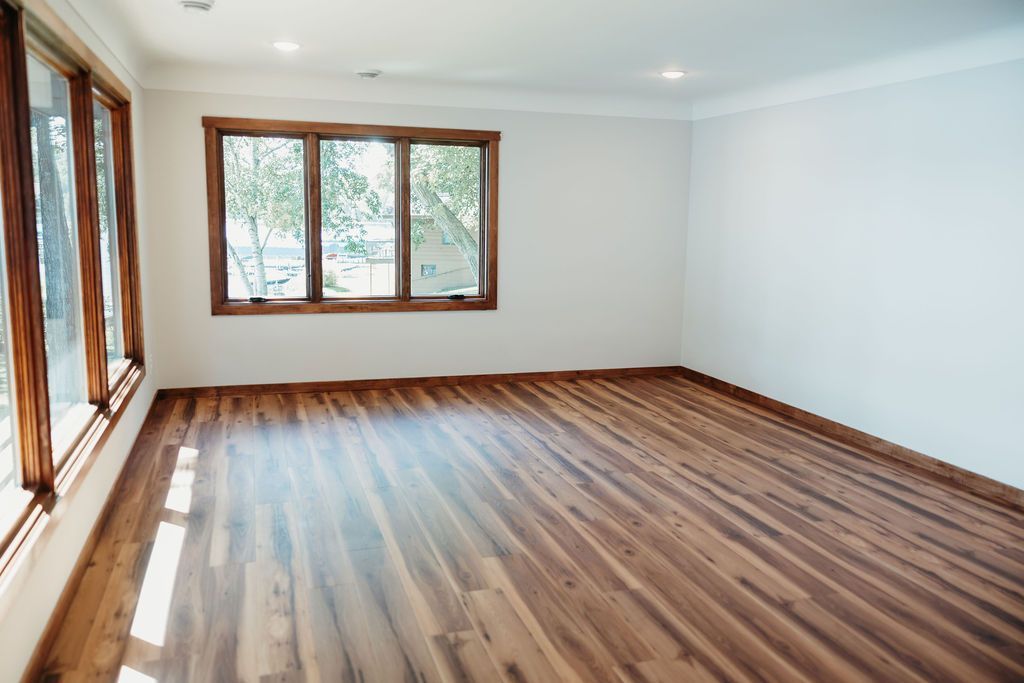Empty room with wood floors and trim, white walls, and three windows.