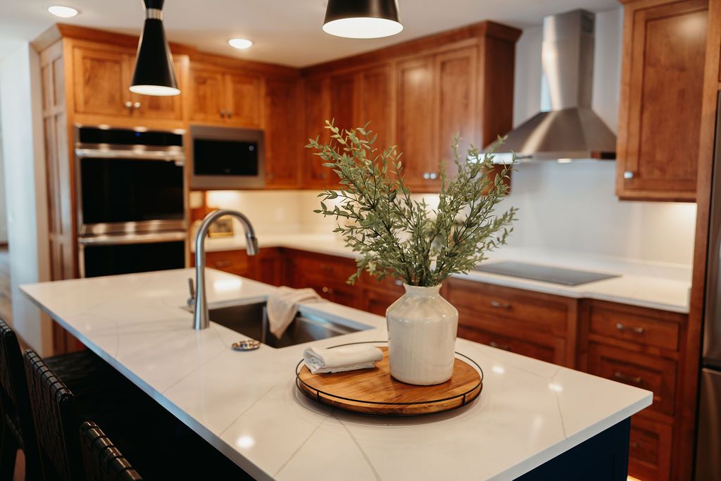 Modern kitchen with a white countertop island, wooden cabinets, and stainless steel appliances.