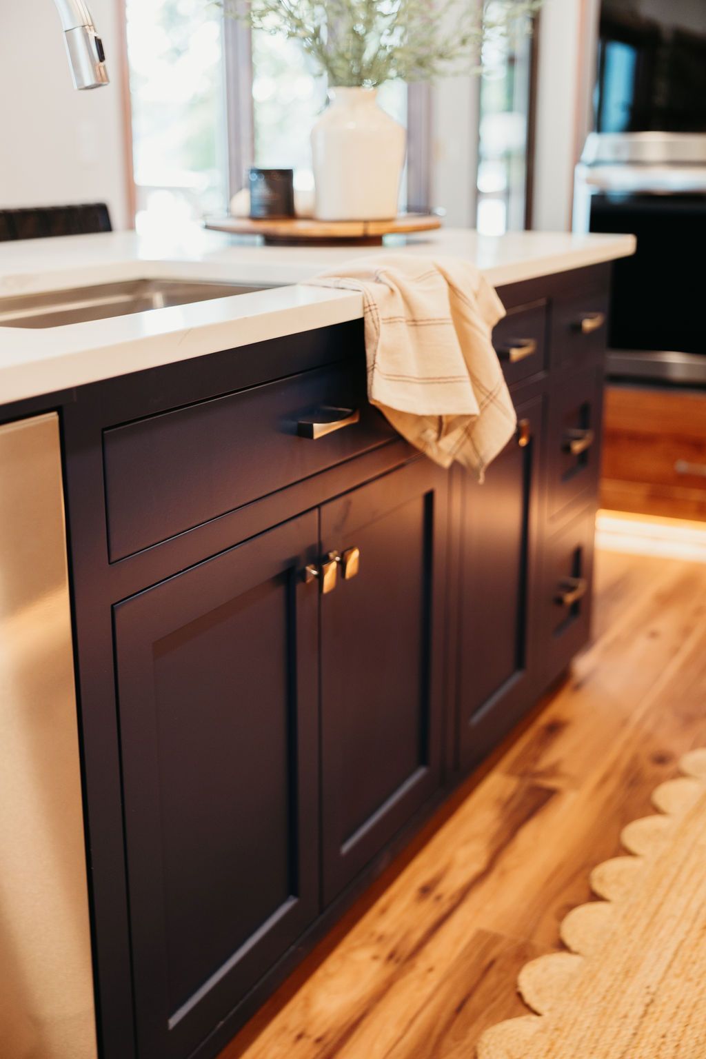 Dark blue kitchen island with a white countertop and gold hardware.
