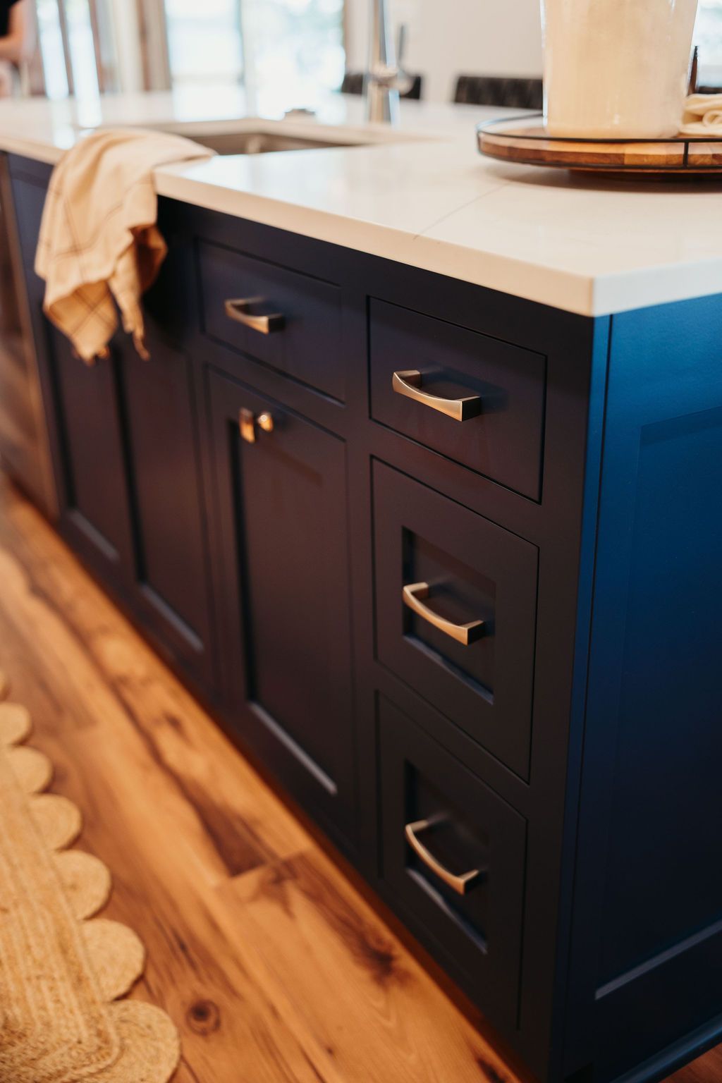 Dark blue kitchen island with gold hardware and white countertop.