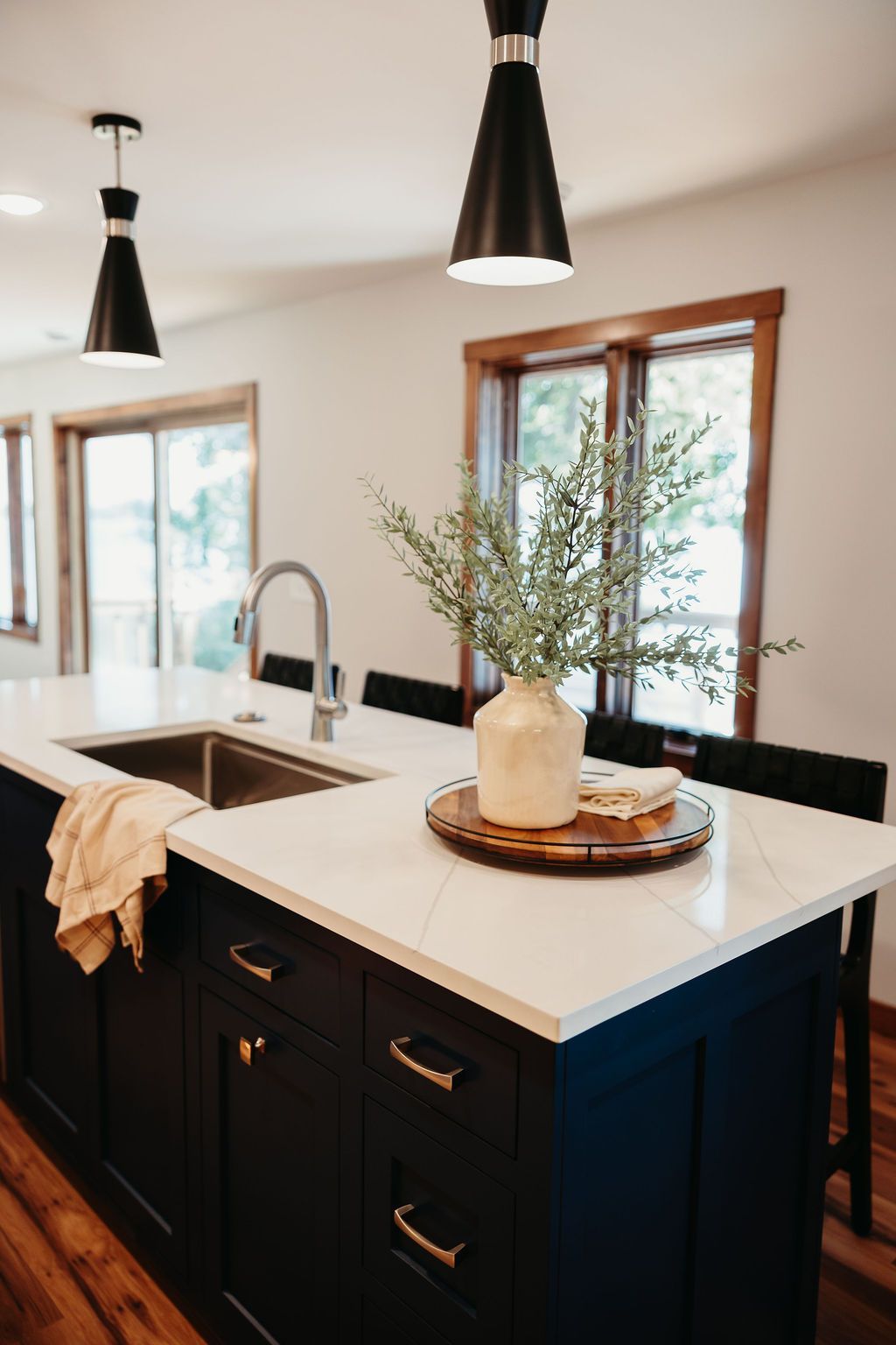 Modern kitchen with a navy island, white countertop, sink, and decorative vase.